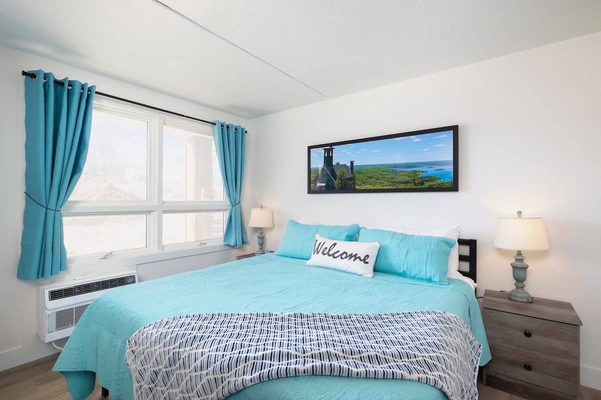 King Suite offering bedside tables with drawers and a place to hang clothes, dresser, plus luggage rack for storage.