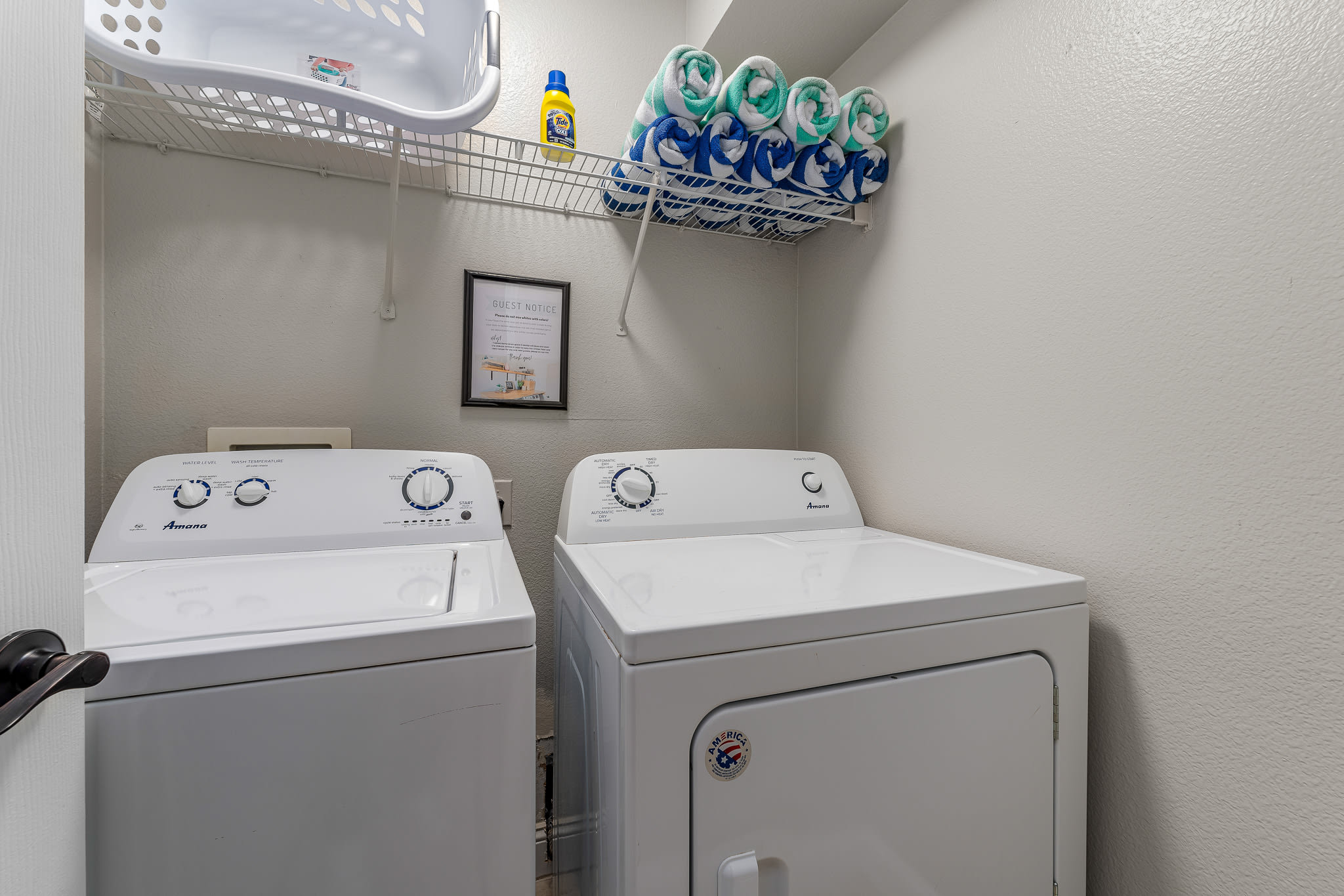 Well-lit laundry area w/ washer, dryer, and open shelving above.