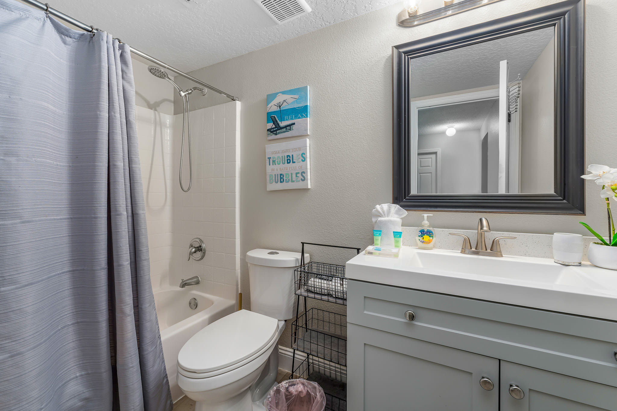Bathroom w/ tub & shower combo, sink, and fresh, neutral styling.