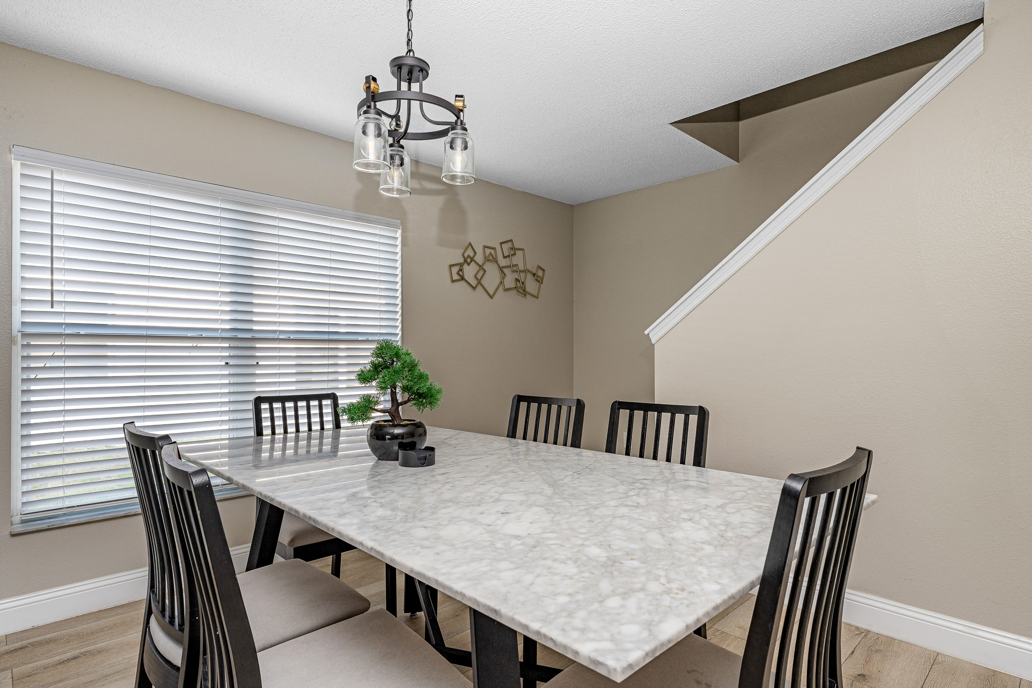 Open dining area w/ large table, modern lighting, and vaulted ceiling overhead.