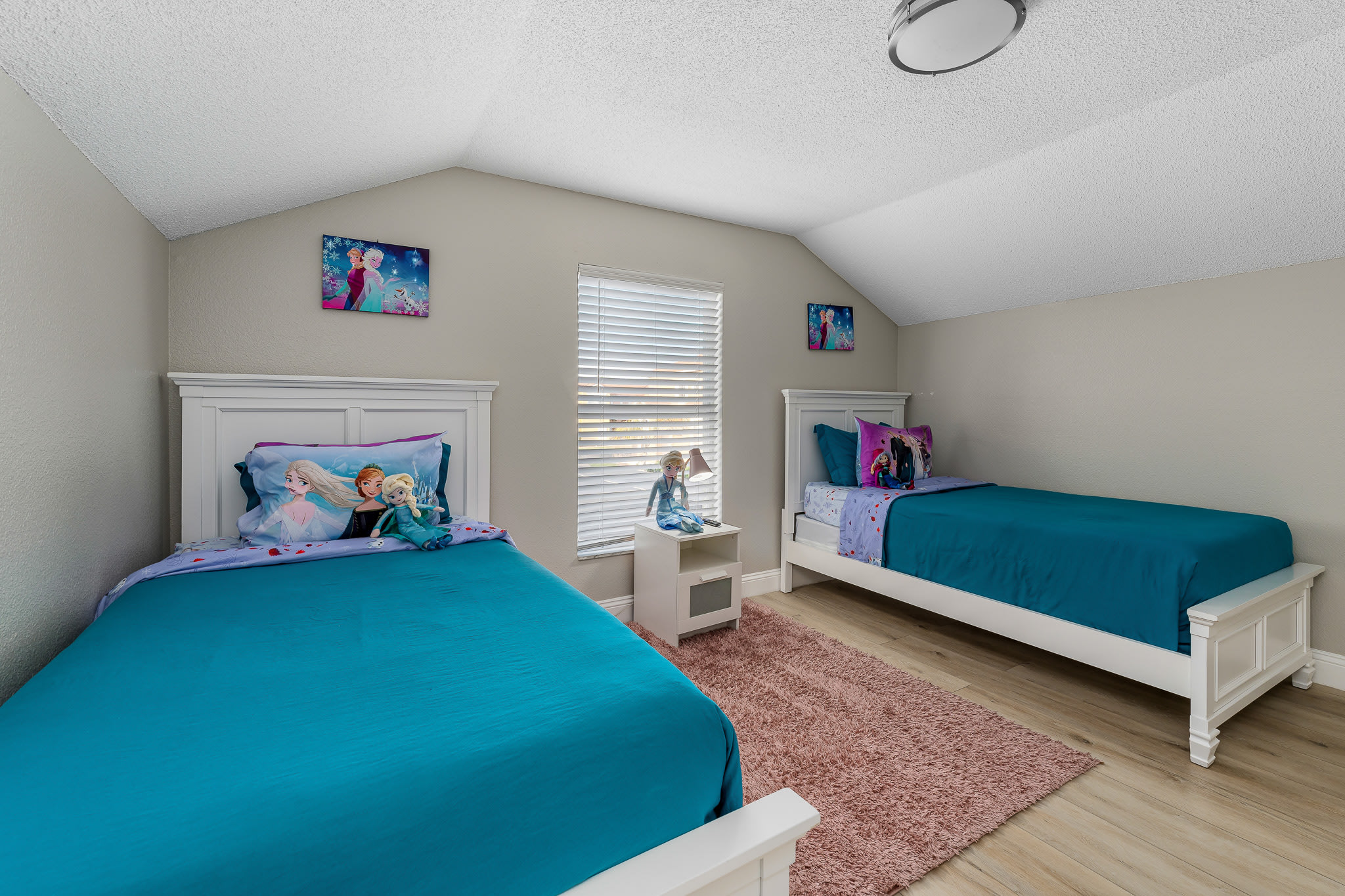 Sunny bedroom w/ twin beds, vibrant accents, and natural light.