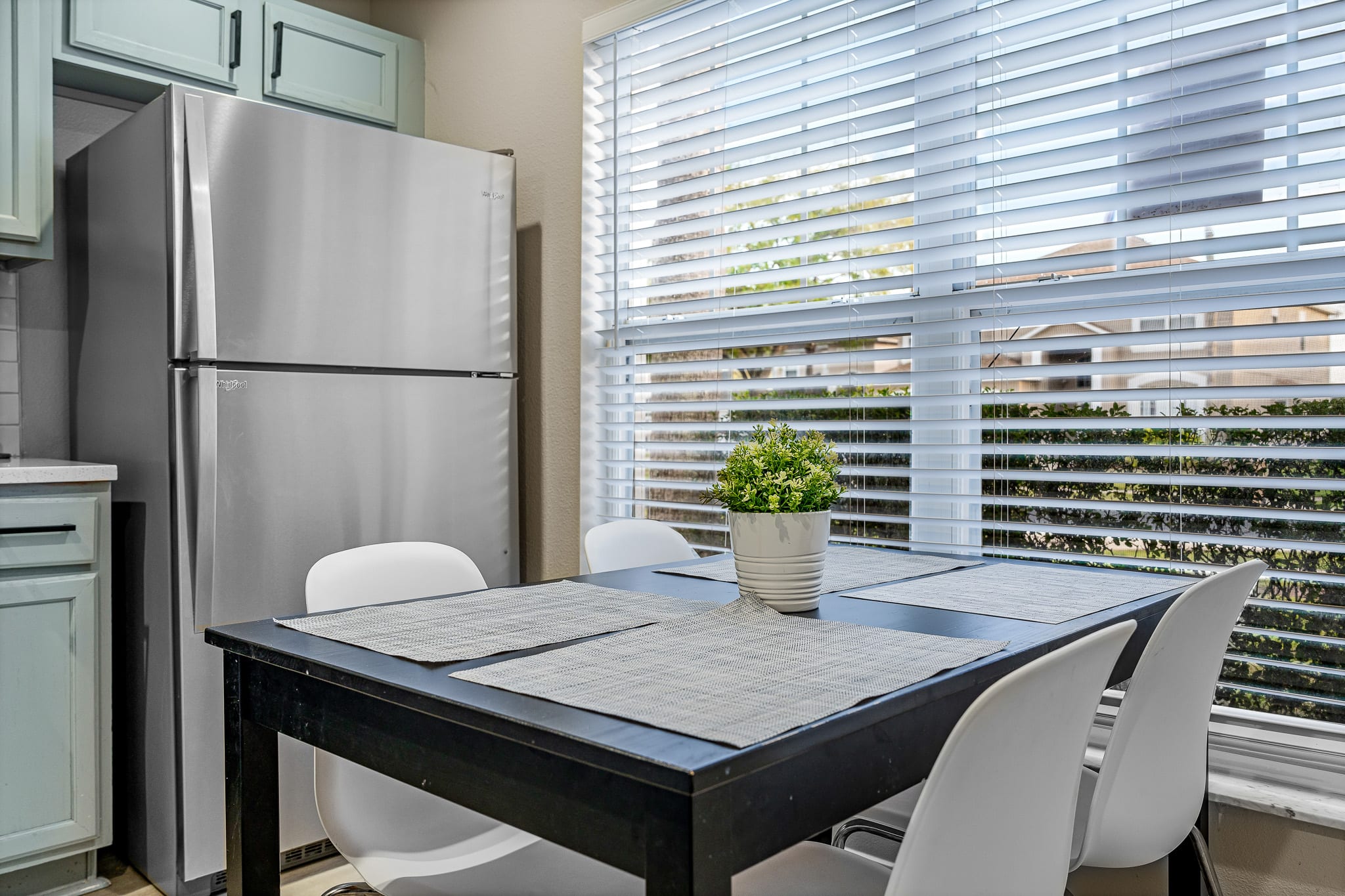 Cozy dining nook w/ modern table, comfortable seating, and natural light from wide windows.