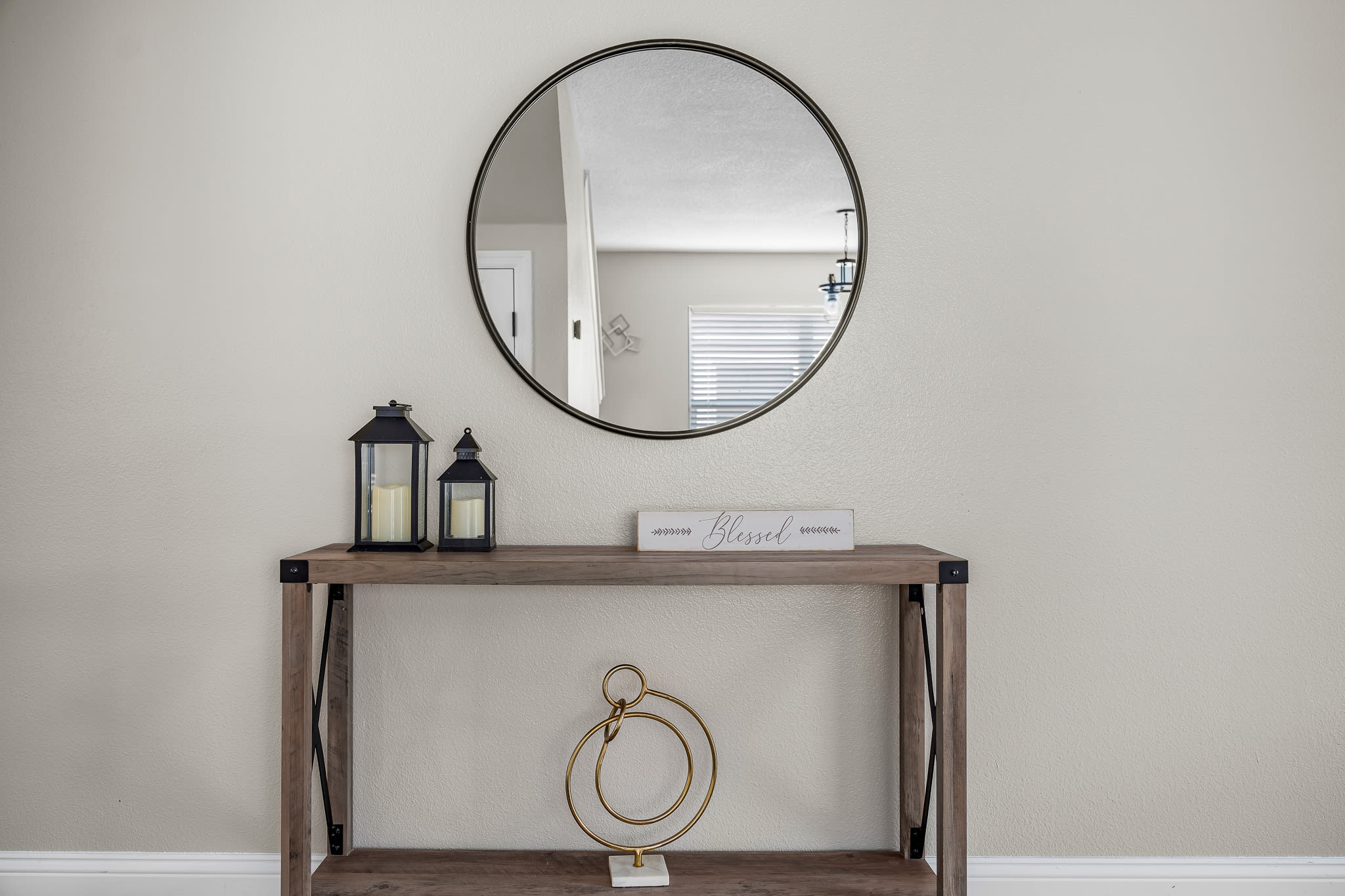Stylish entry console w/ round mirror and simple, modern decor.