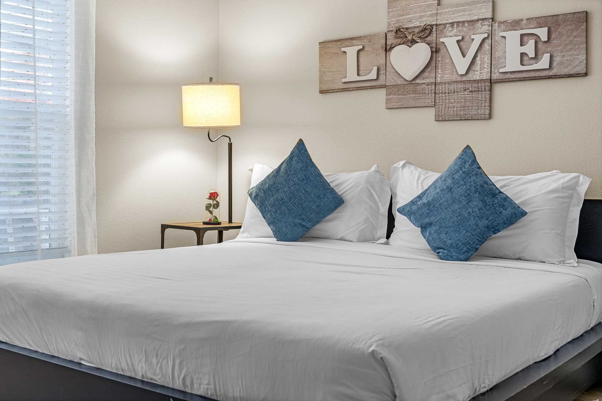 Bright bedroom w/ crisp white bedding, accent pillows, and charming wall decor.