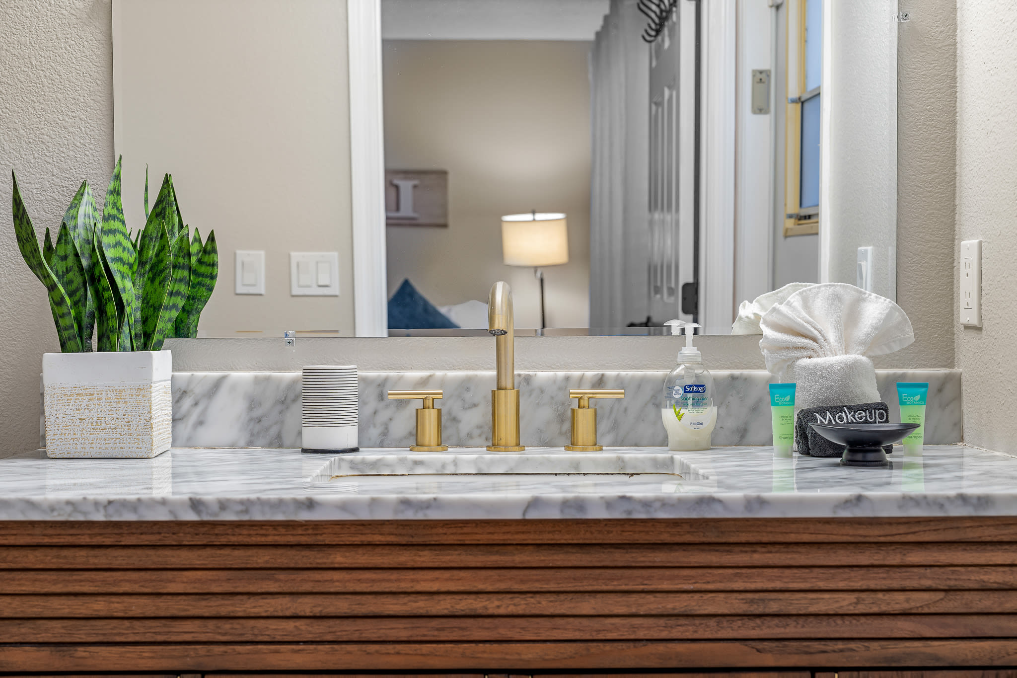 Bathroom vanity w/ sink, large mirror, and thoughtful decorative touches.