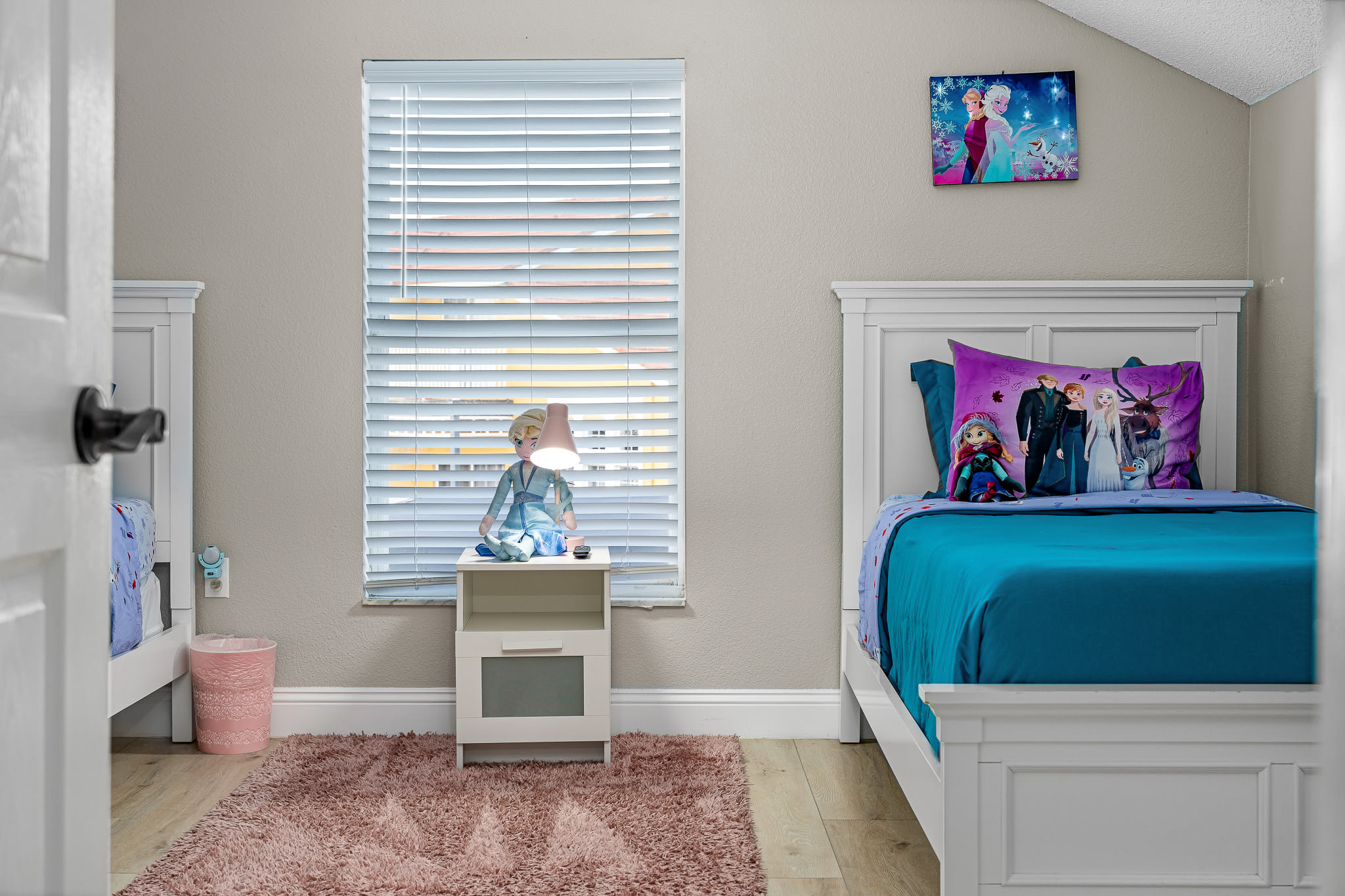 Sunny bedroom w/ twin beds, vibrant accents, and natural light.