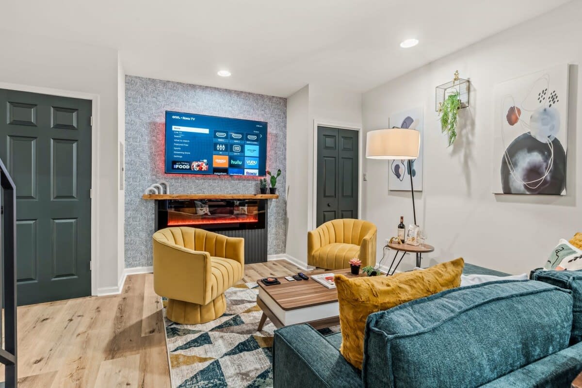 Relax in the stylish living room, featuring a large Roku TV and modern decor. It's an ideal spot for unwinding after a day of exploring, with comfortable seating and a chic ambiance.