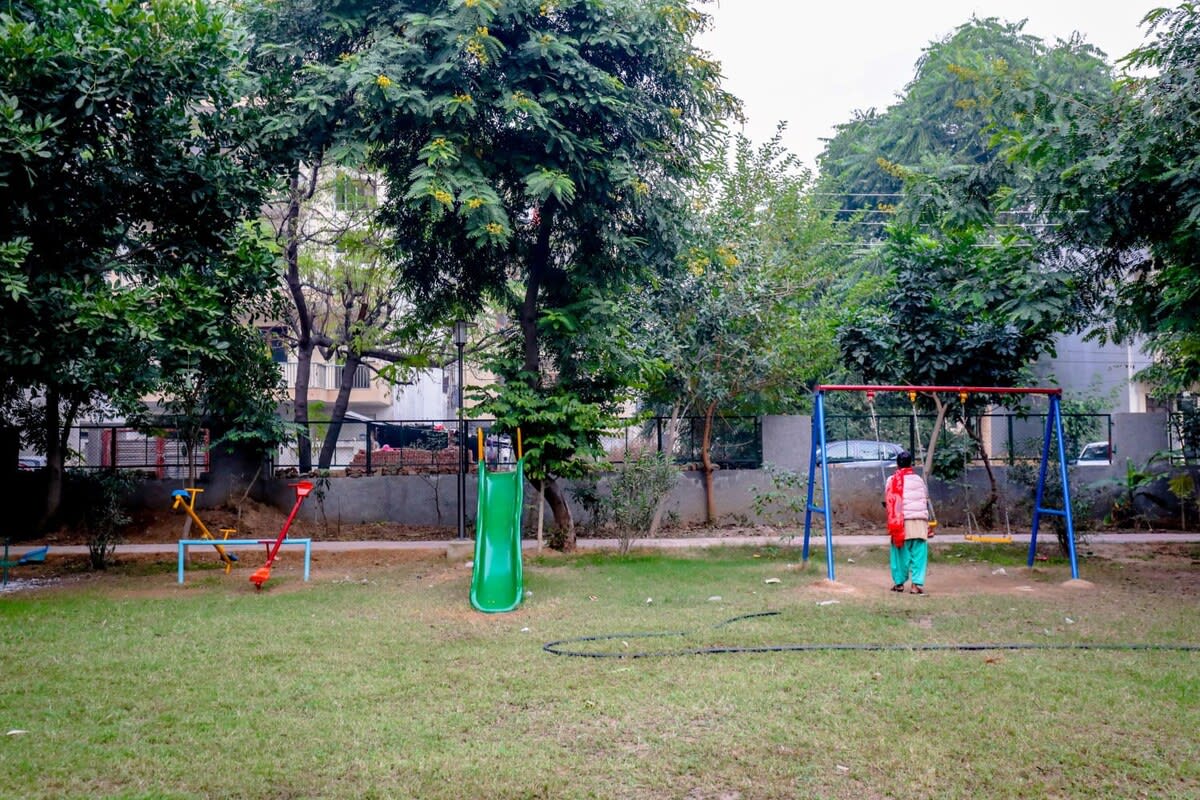 A vibrant park scene featuring children enjoying rides and games, with colorful play equipment and joyful laughter filling the air