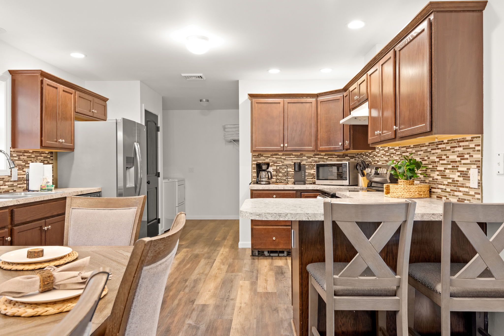 This well-equipped kitchen features rich wood cabinetry, a stone backsplash, and an island with bar seating ideal for social cooking and casual bites.