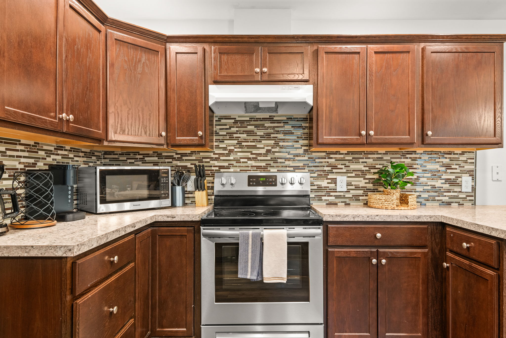 Classic wood cabinetry pairs with a modern backsplash and stainless steel appliances, offering everything you need for home-cooked meals or quick snacks.