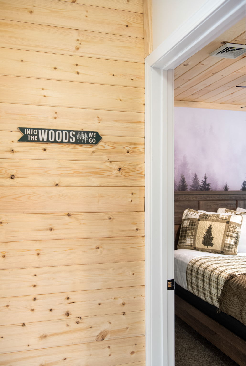 A Touch of Cabin Whimsy
A wood-paneled hallway leads into your cozy upstairs bedroom complete with a fun "Into the Woods" sign that sets the tone for a relaxing mountain escape.