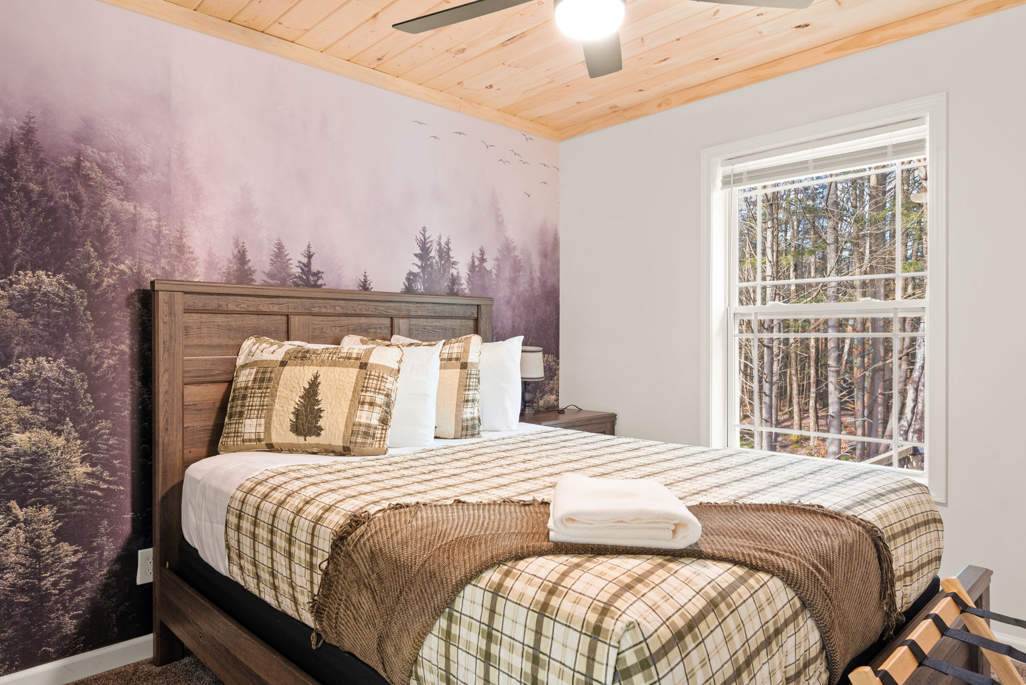 Forest-Inspired Cozy Haven
This serene space features a stunning tree-lined mural, plaid bedding, and warm wood finishes giving you peaceful cabin vibes with a playful twist.