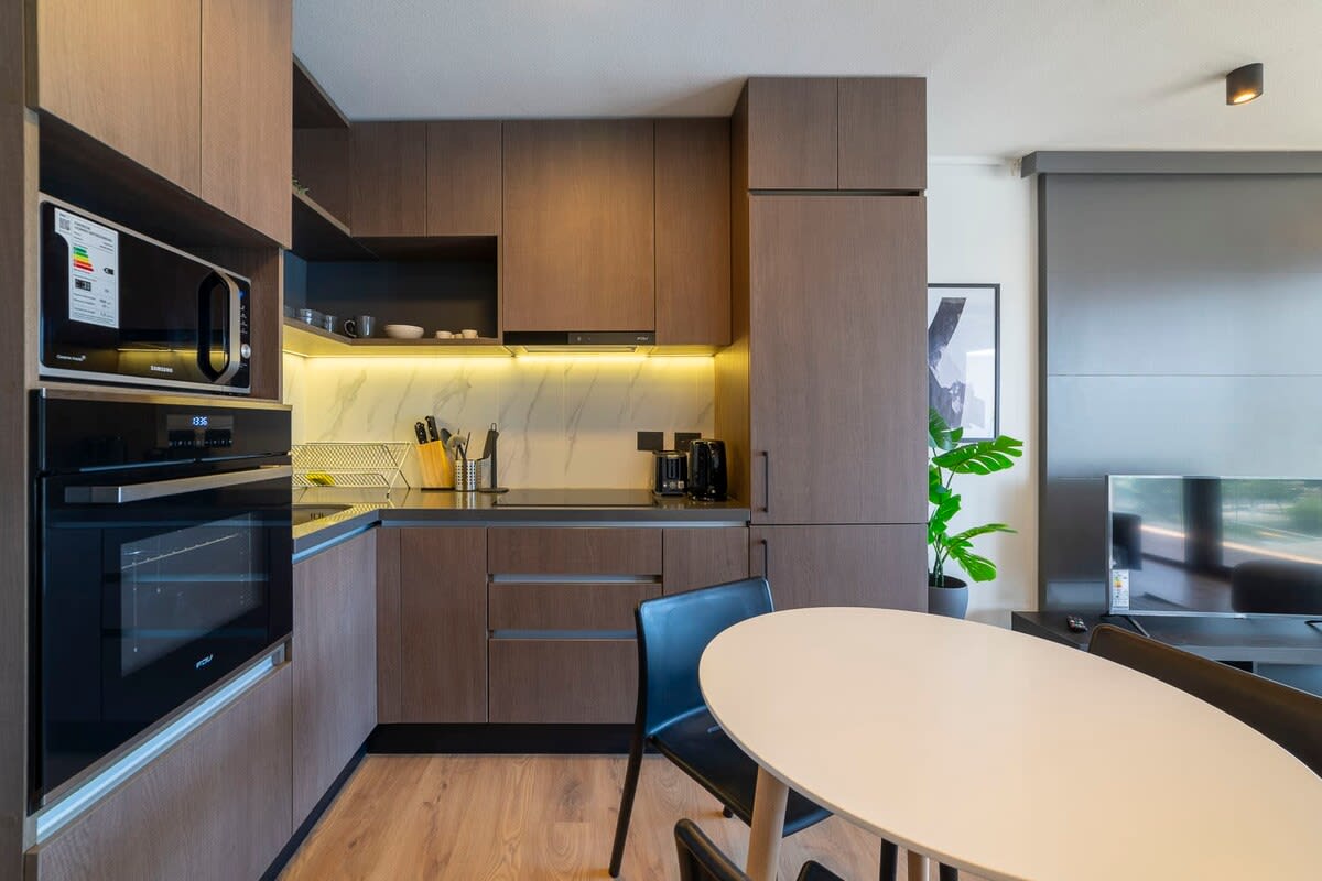 Sleek, modern kitchen with all essentials for a cozy meal, complemented by a stylish dining area and TV corner.