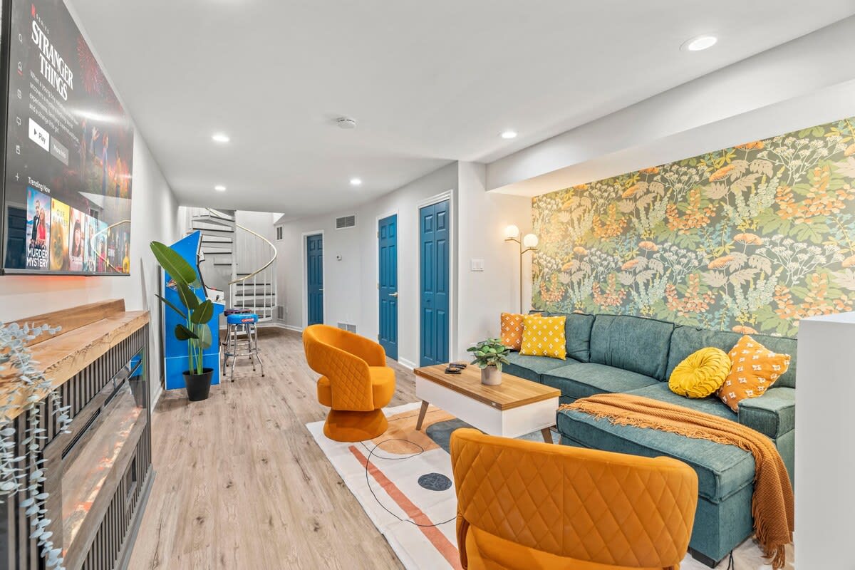 Immerse yourself in comfort and style in this chic living area with vibrant accents. You will love the cozy seating, inviting wallpaper, and modern entertainment setup, perfect for unwinding after a day of exploring!