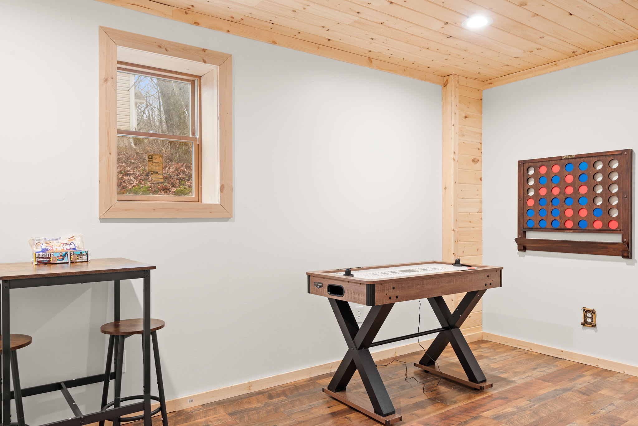 A bright and inviting game space with natural wood accents, offering shuffleboard, a classic game wall, and seating.