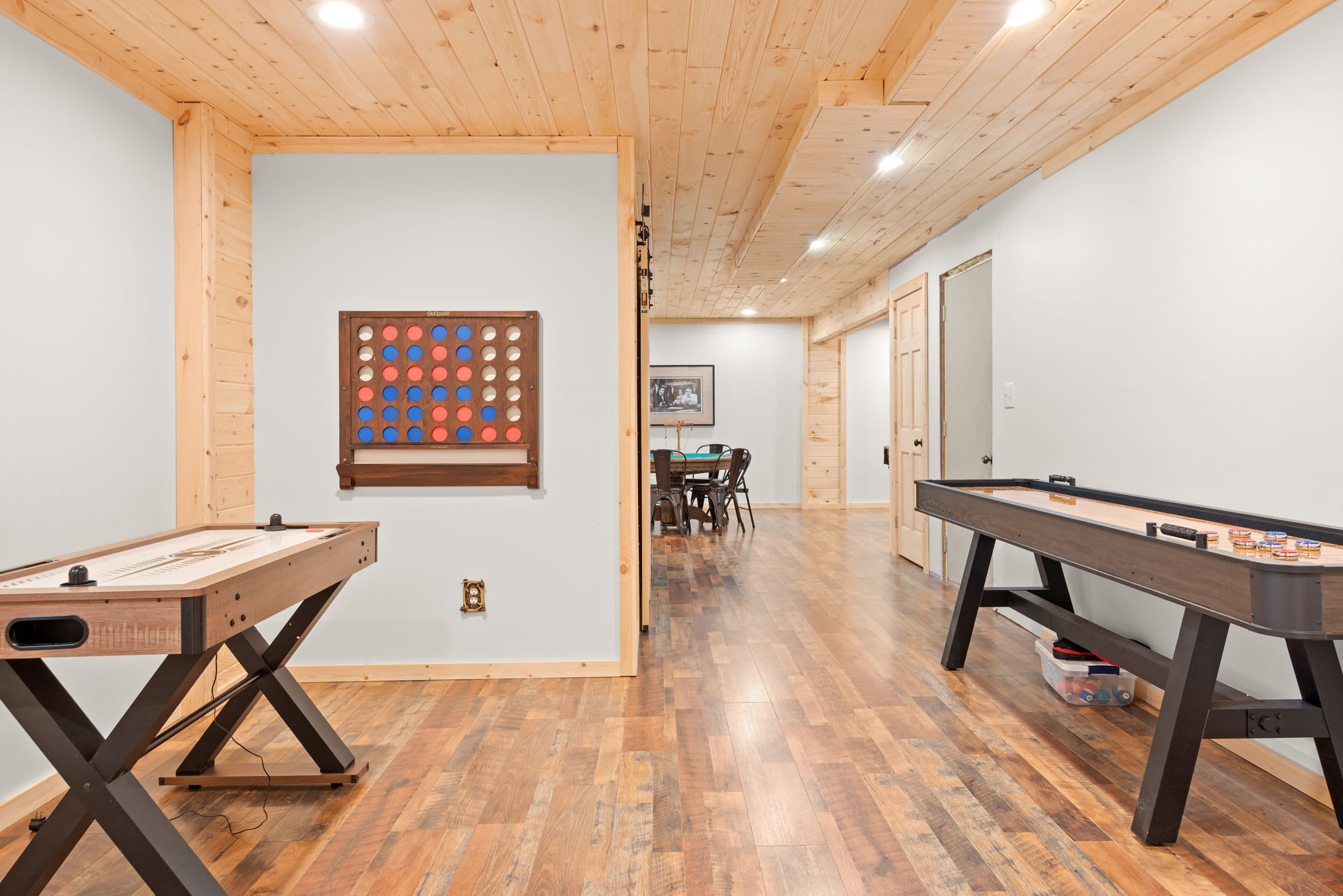 A thoughtfully arranged game room featuring both shuffleboard and an oversized Connect Four wall for hours of fun.