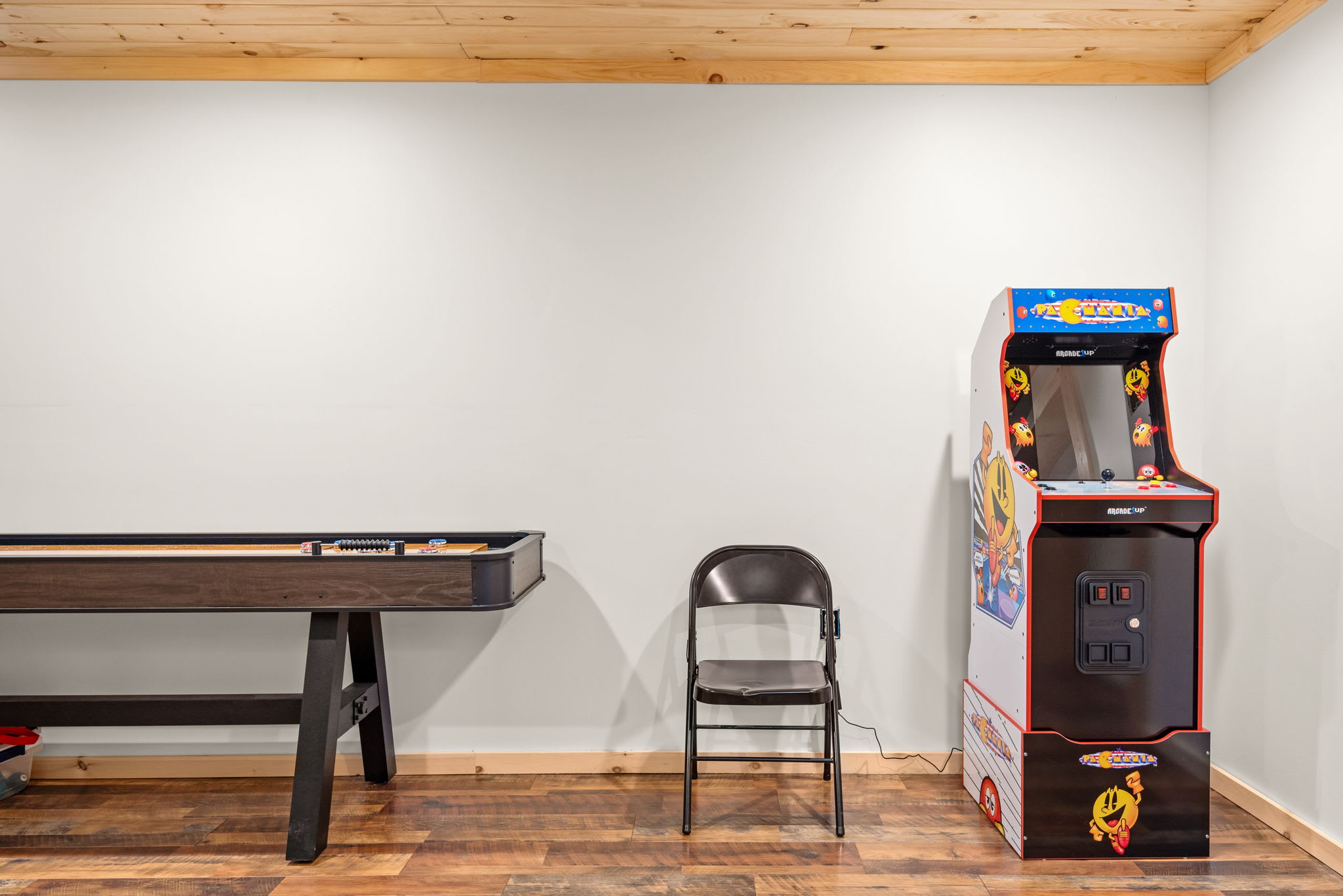 A fun-packed corner featuring a vintage Pac-Man arcade machine and a shuffleboard table, perfect for endless entertainment.