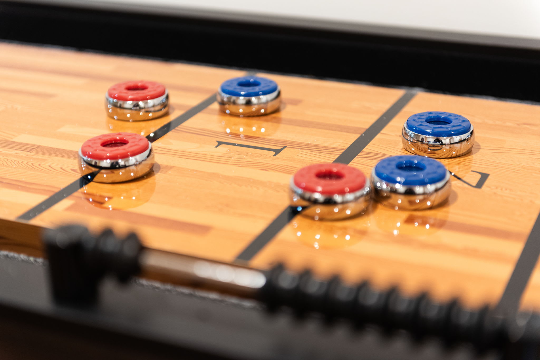 A detailed shot of the shuffleboard pieces, inviting friendly competition in this cozy game room.