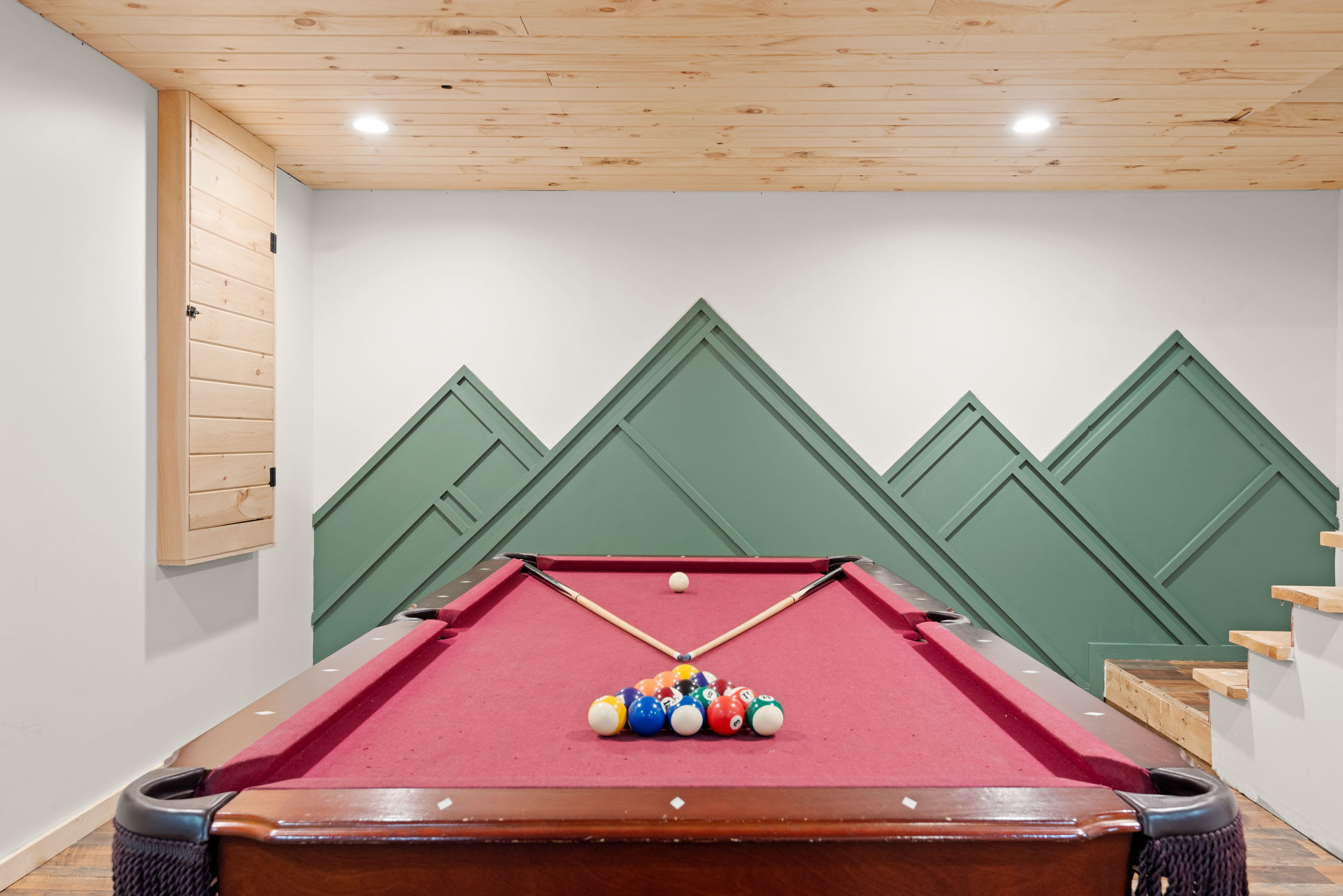 A beautifully set pool table against a mountain-inspired accent wall, making every game feel like a special event.