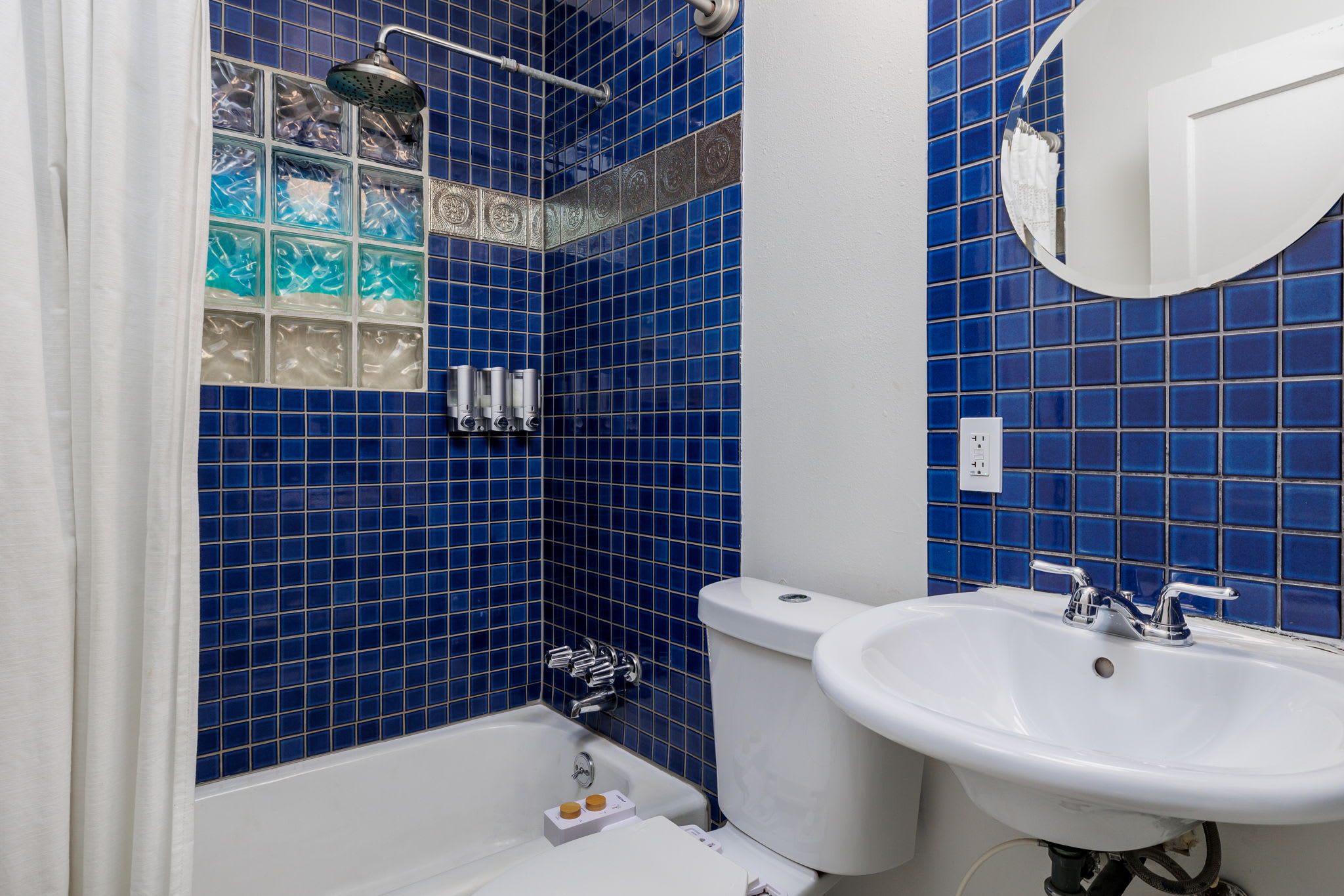 Bathroom includes a bidet attachment for the toilet as well as a waterfall shower head. 