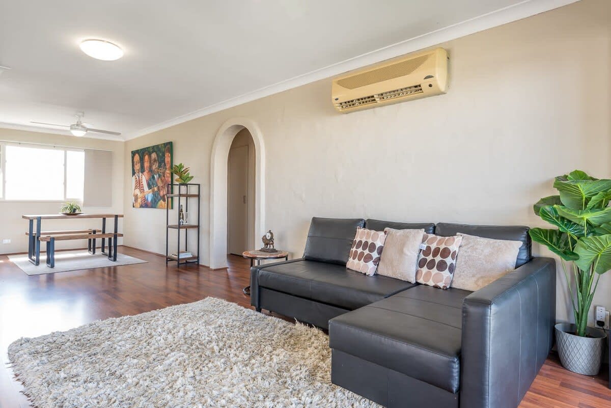 The living room offers a comfy couch situated in a spacious open-plan with access to a private balcony, perfect for unwinding during the day or at night