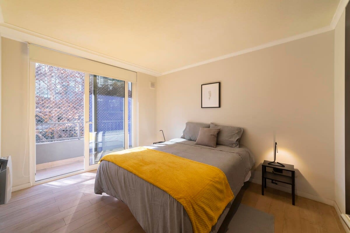 Relax in this cozy bedroom with a sunny balcony view, perfect for unwinding after a day exploring the city.