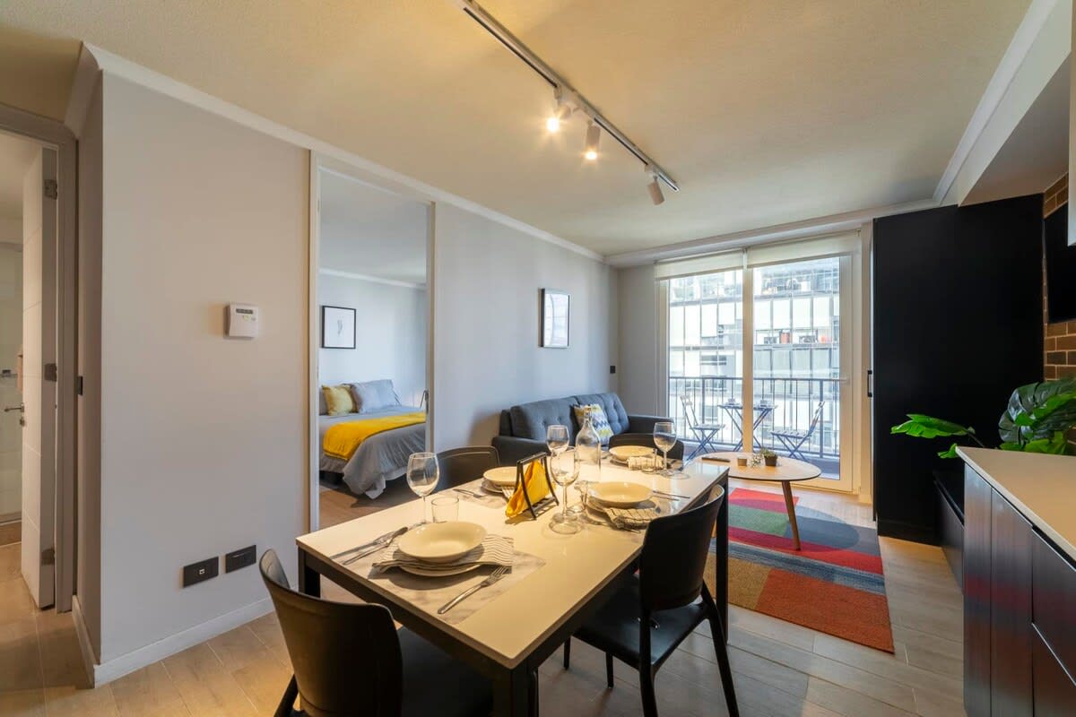 Bright and modern living space with a cozy sofa, dining area, and balcony access, perfect for relaxing after a day exploring the city.