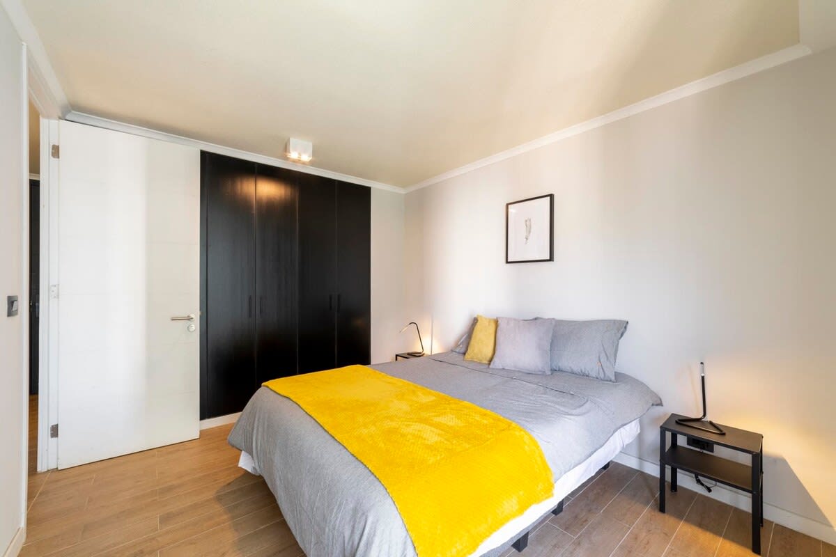 Relax in this stylish bedroom with a vibrant touch of yellow, perfect for a cozy retreat.