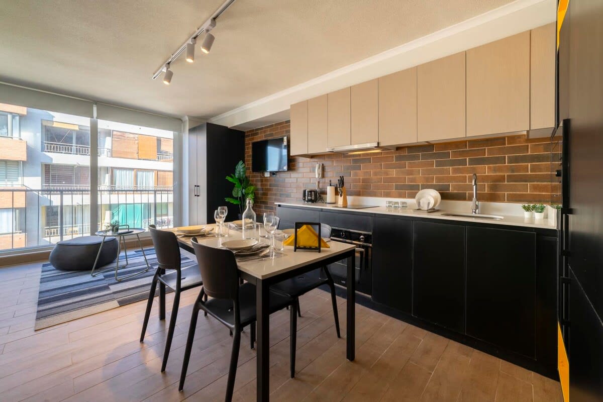 Modern studio kitchen with ample natural light and stylish decor, perfect for a cozy meal with a view.