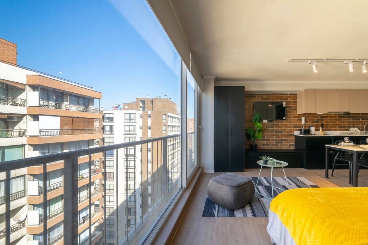 Experience urban living with stunning city views from this modern studio apartment, complete with a cozy seating area and fully equipped kitchenette.