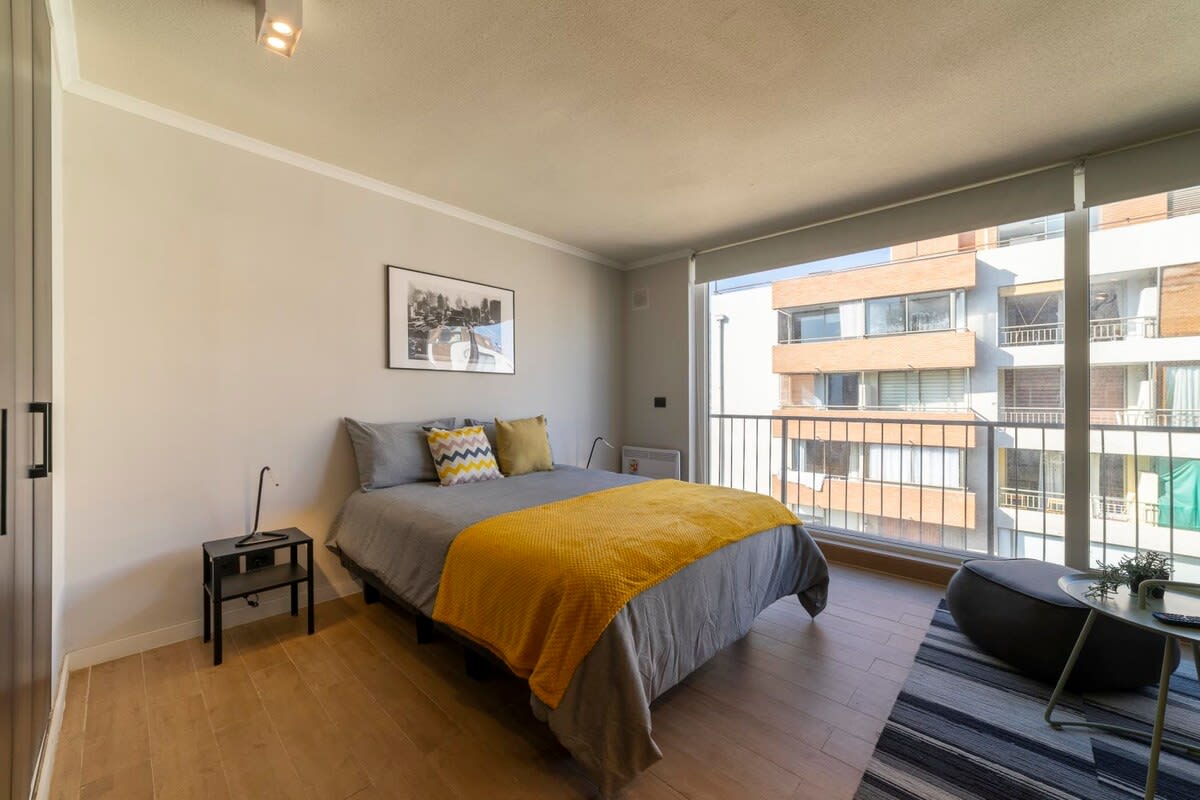 Bright and cozy studio with a modern touch, featuring a comfy bed and a large window for natural light.