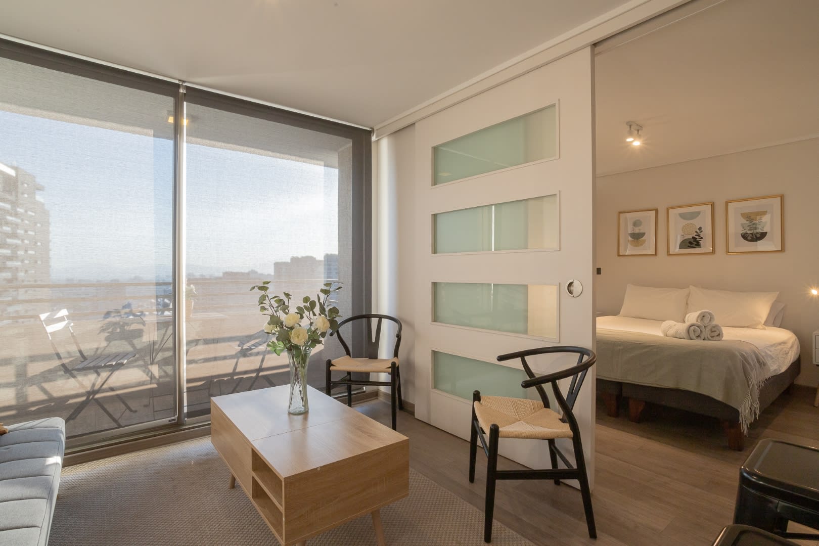 Bright and inviting living space with a view into a cozy bedroom, perfect for relaxing after exploring the city.