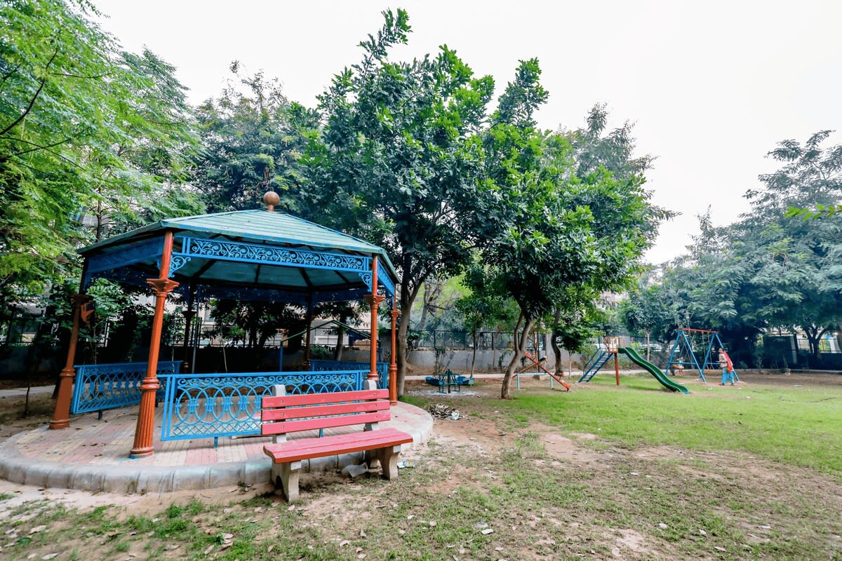 A vibrant park scene featuring children enjoying rides and games, with colorful play equipment and joyful laughter filling the air