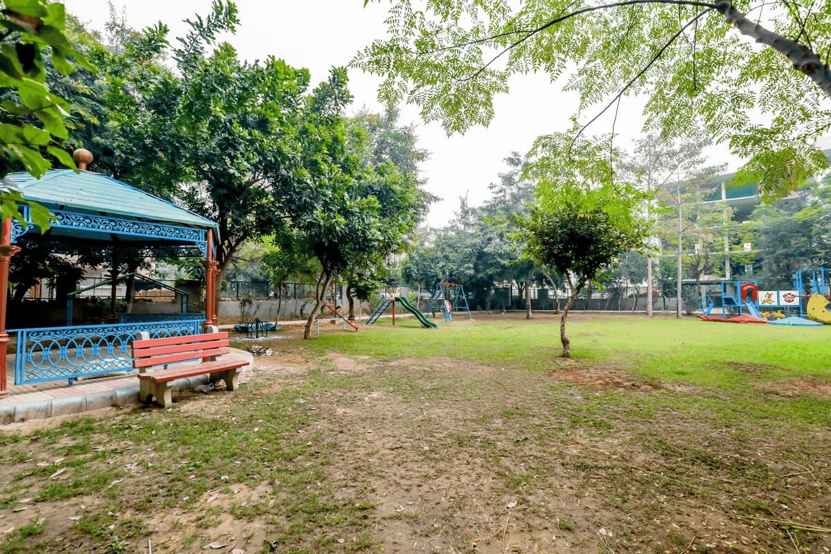 A vibrant park scene featuring children enjoying rides and games, with colorful play equipment and joyful laughter filling the air