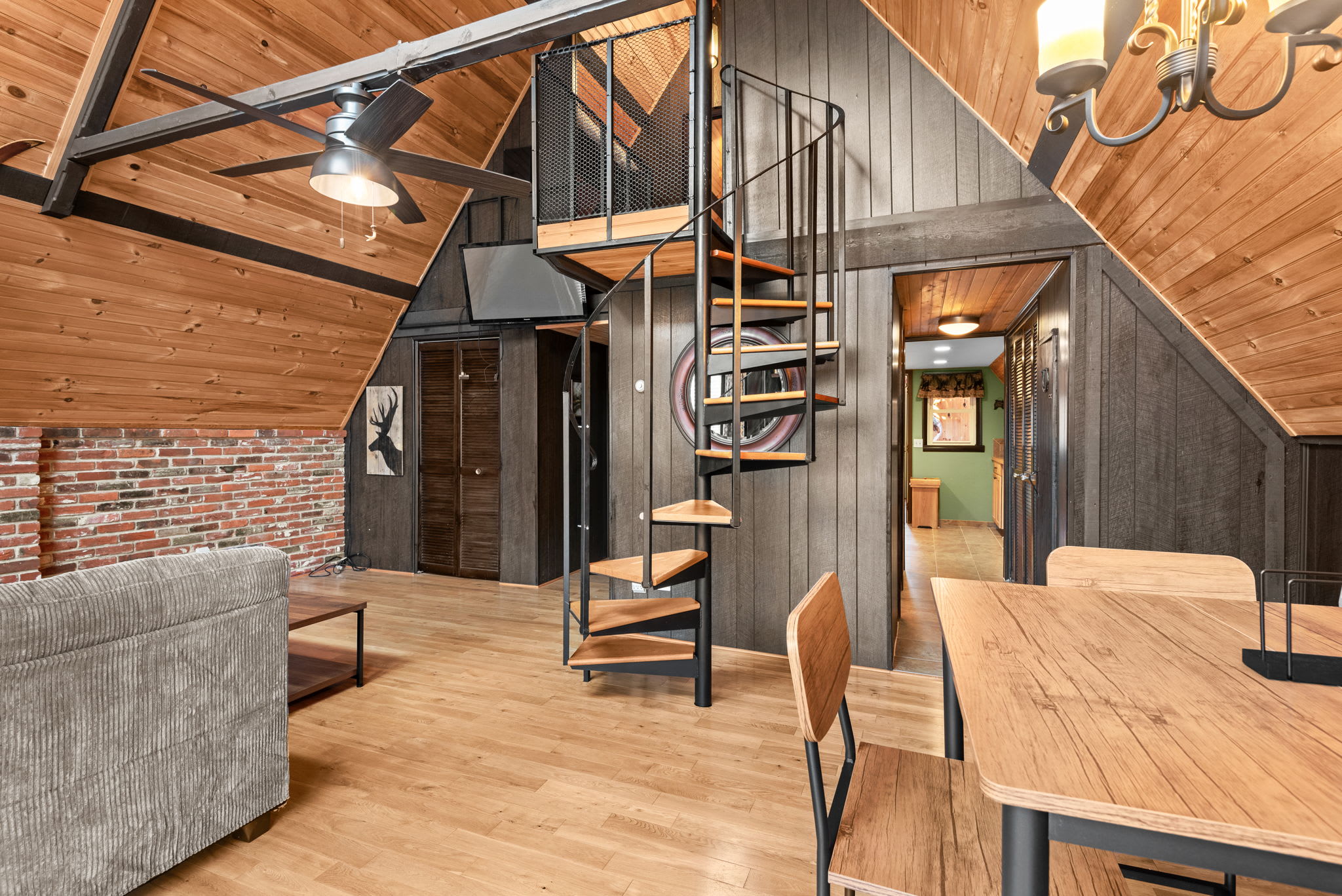 A rustic yet modern retreat with a comfortable sectional, warm wood paneling, and a crackling fireplace.