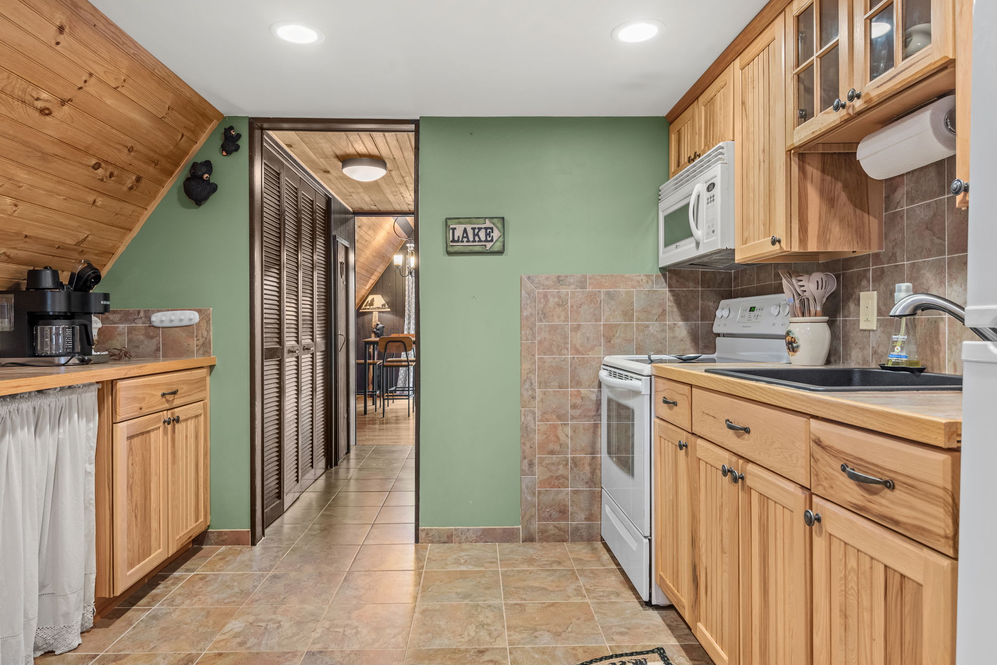 A fully equipped kitchen featuring natural wood cabinets, a tiled backsplash, and a cozy, cabin-style ambiance.