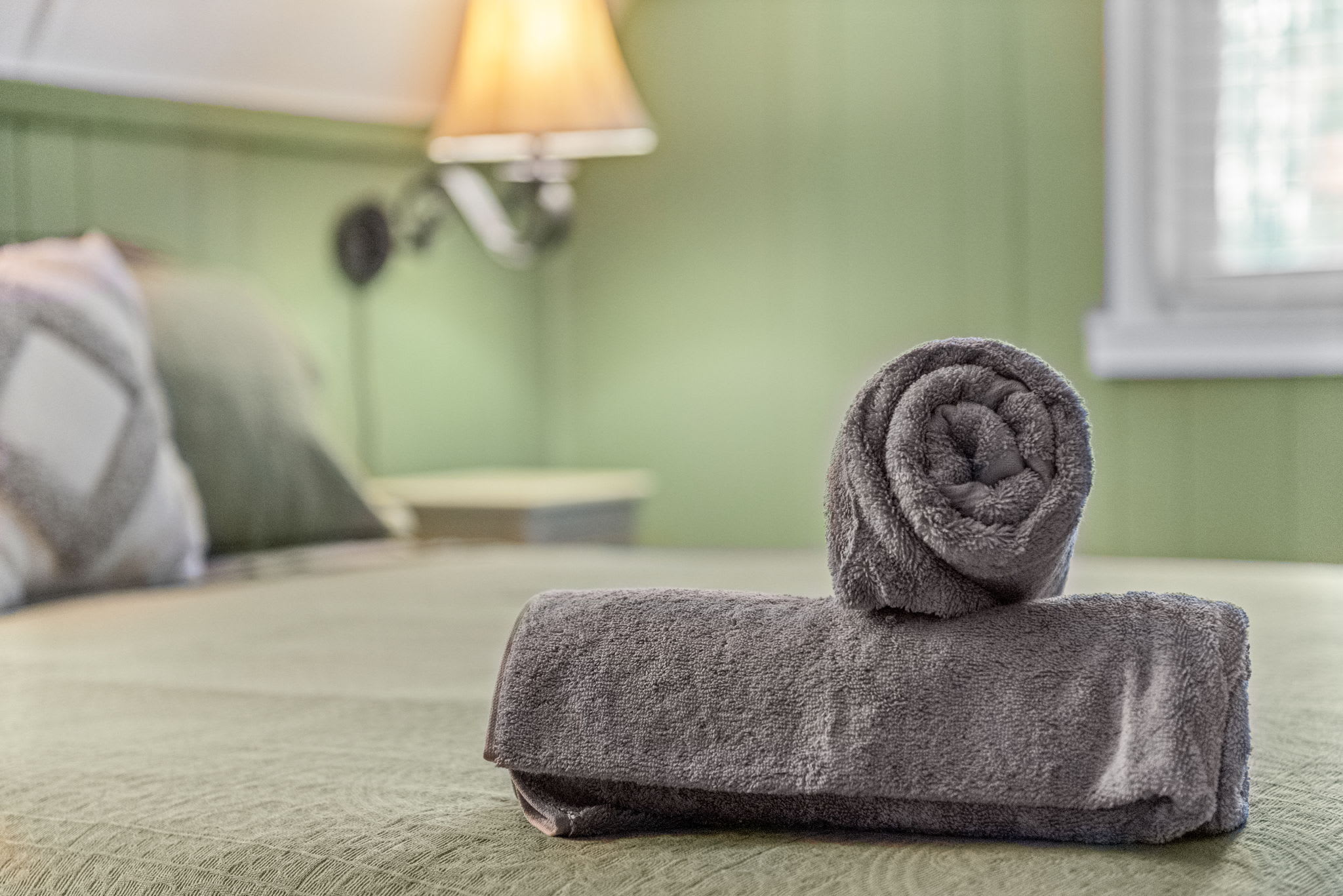 A close-up of the neatly prepared bed, highlighting soft towels and an elegant pillow arrangement.