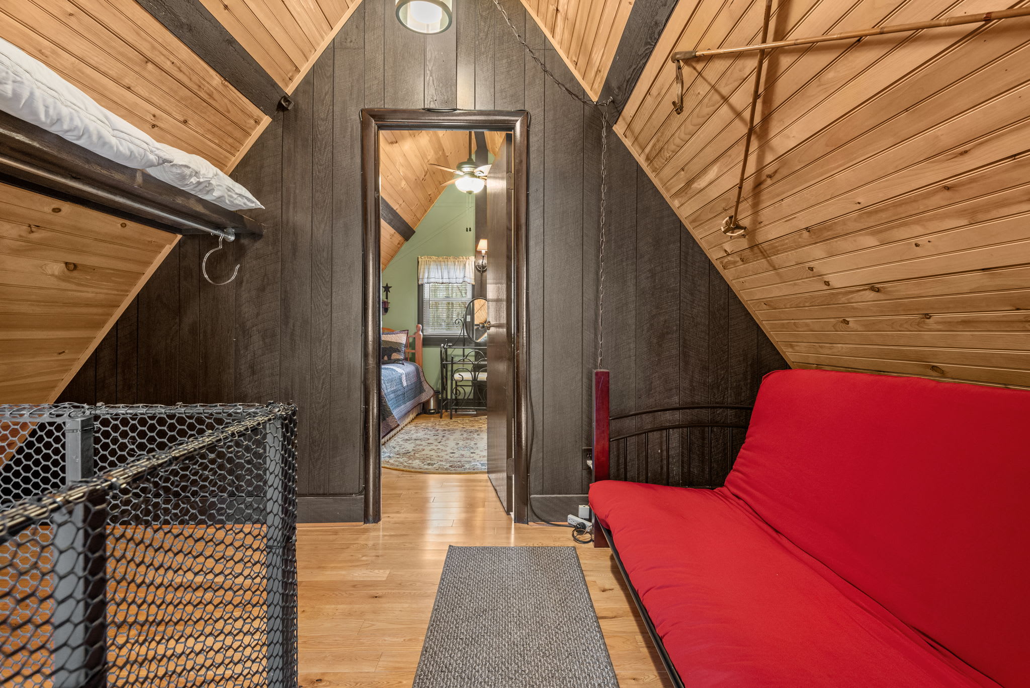 A cozy loft space with a red futon, perfect for lounging or extra sleeping space.