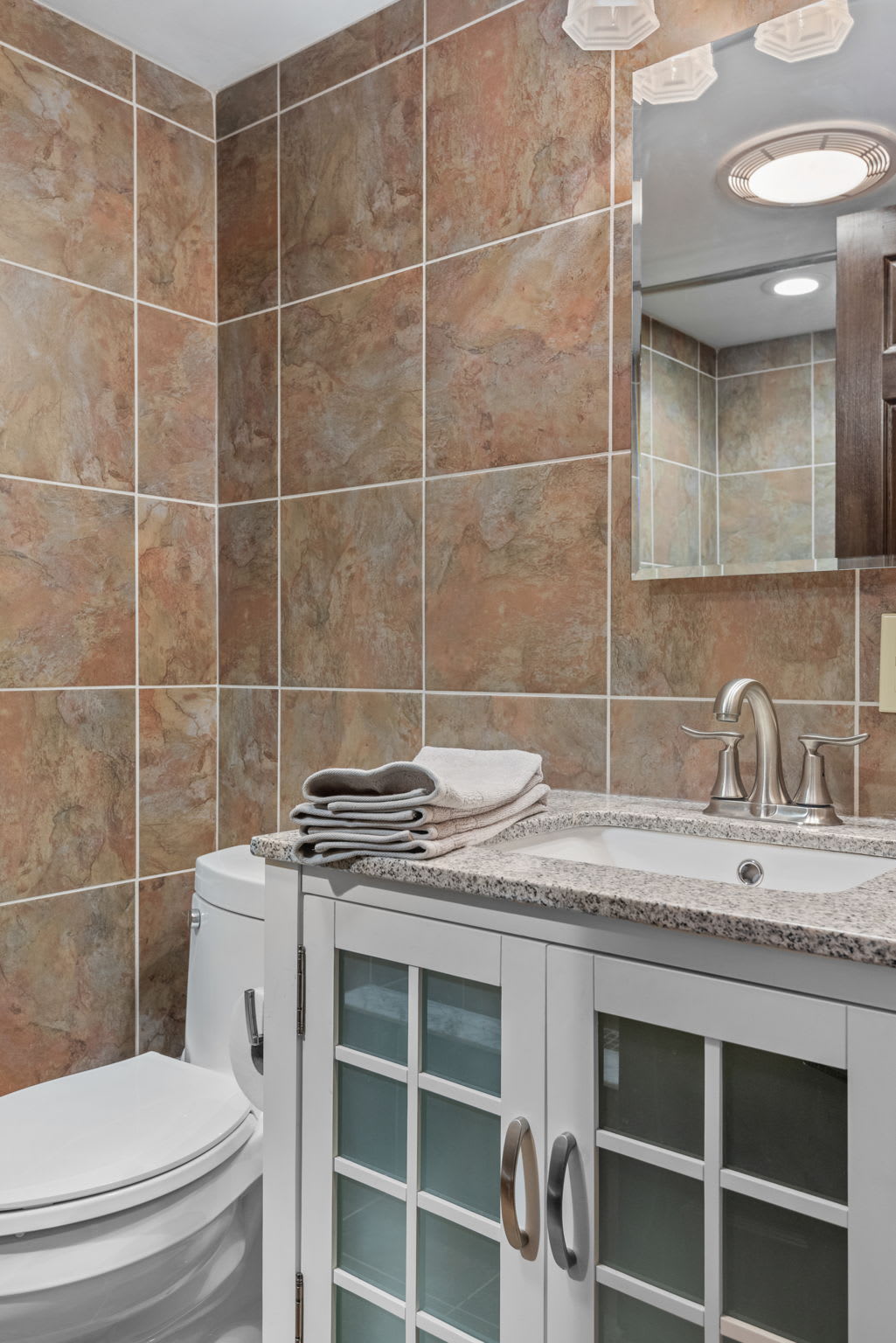 A bright and inviting space with a granite countertop, modern faucet, and fresh towels.