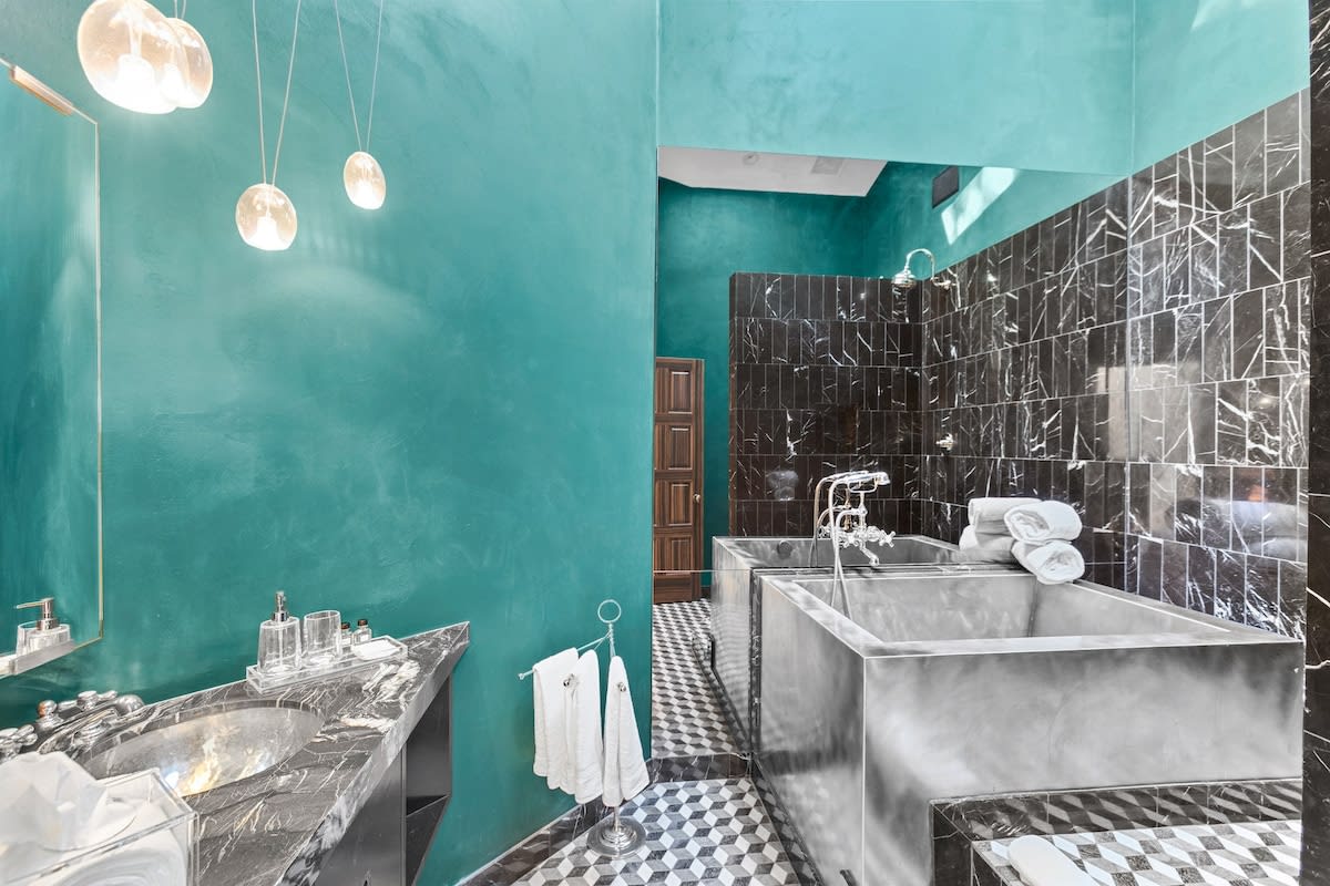One of a kind steel bathtub and marble tile wall