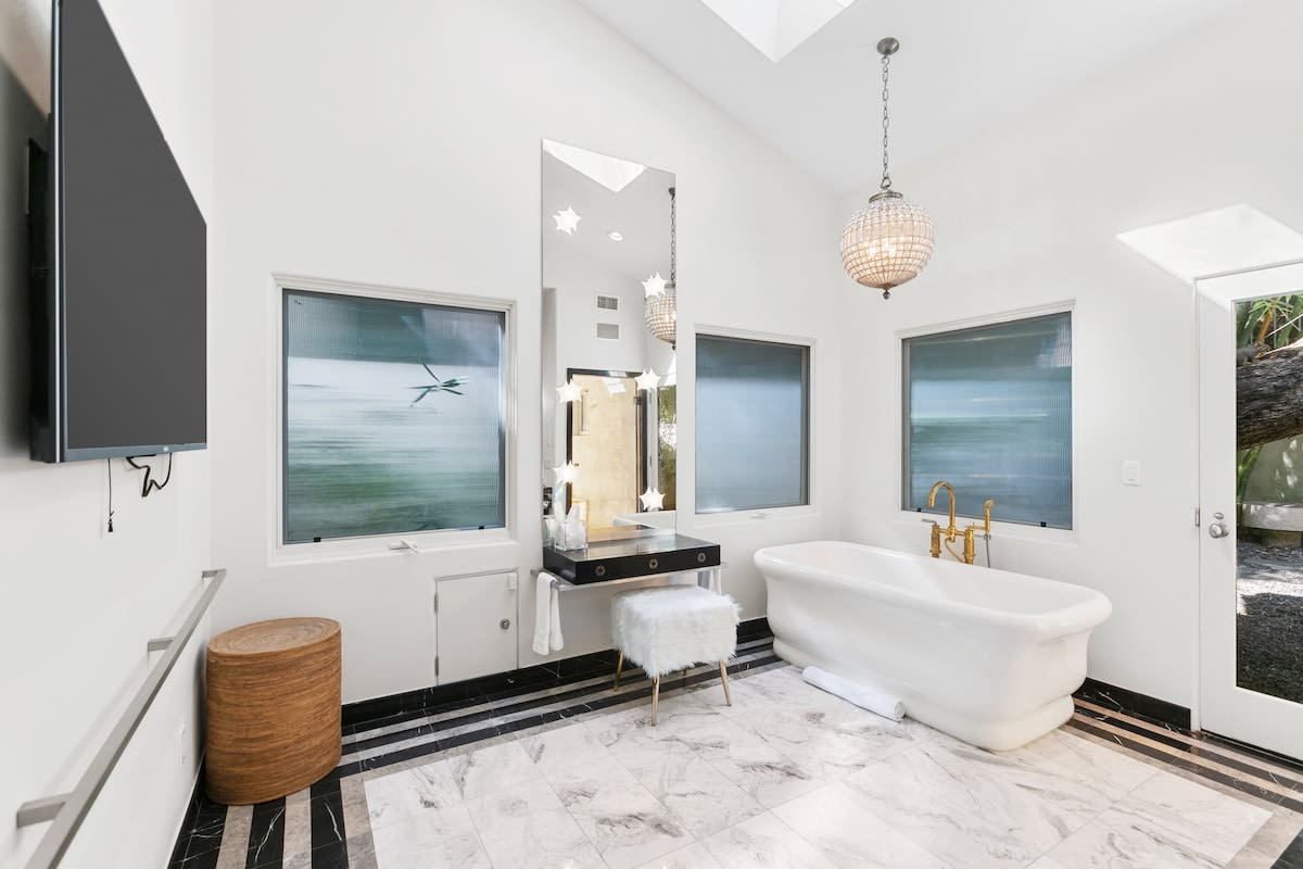 Master bathroom with make up table, bathing tub, and smart TV