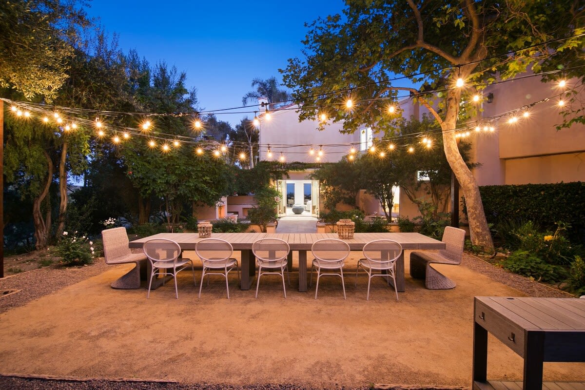 Outdoor dining space that seats 12 with warming string lights.