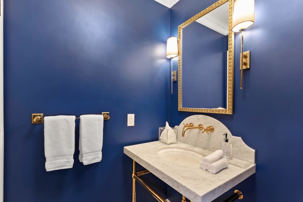 Eye catching royal blue bathroom with bronze accents and furnishings.