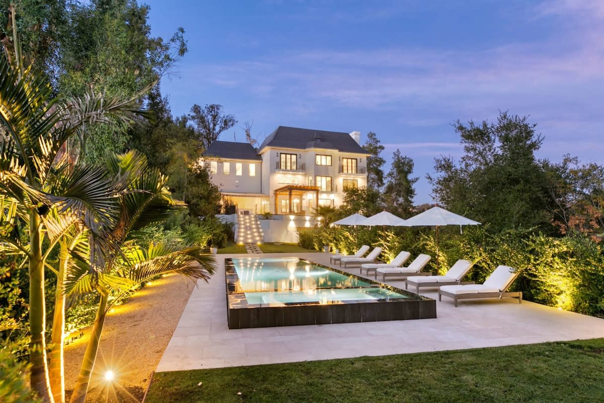Backyard view of this gorgeous Chateau featuring lush California greenery and a zero-edge pool and lounge area.