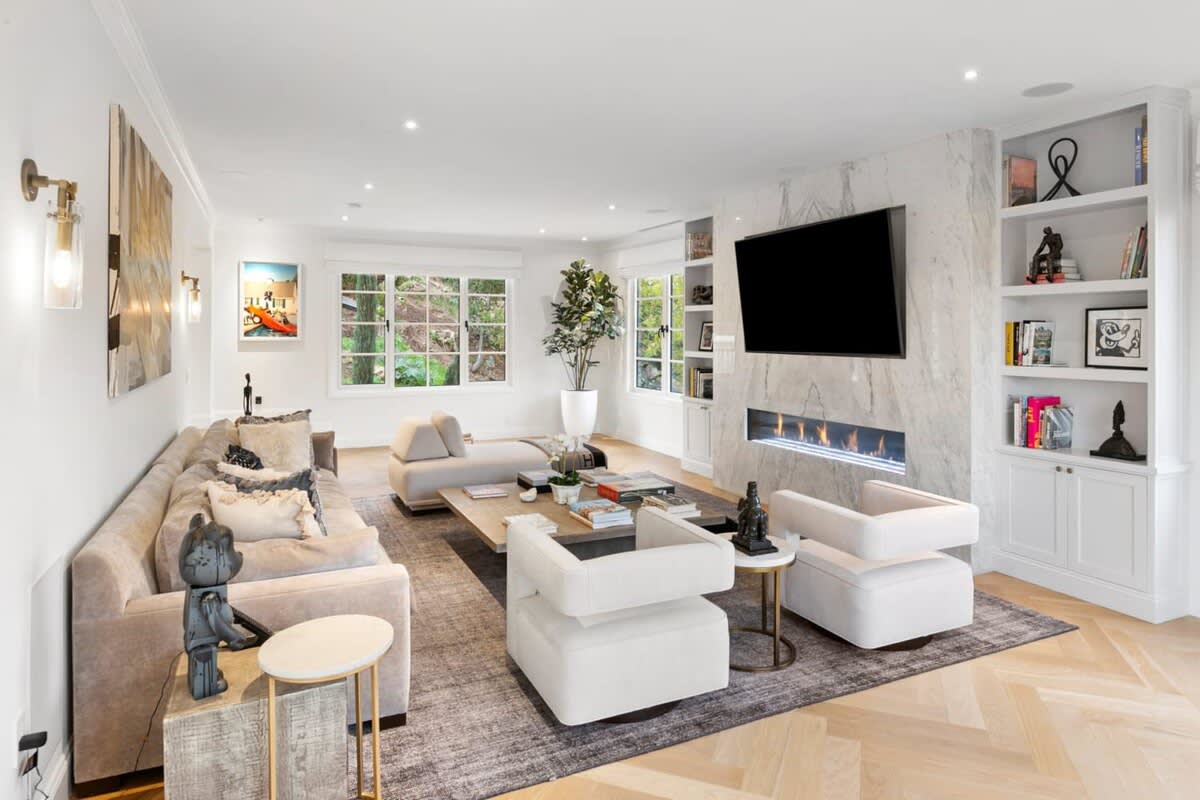 Comfort and entertainment are amplified by art work, technology and a warm fire in this spacious living room.
