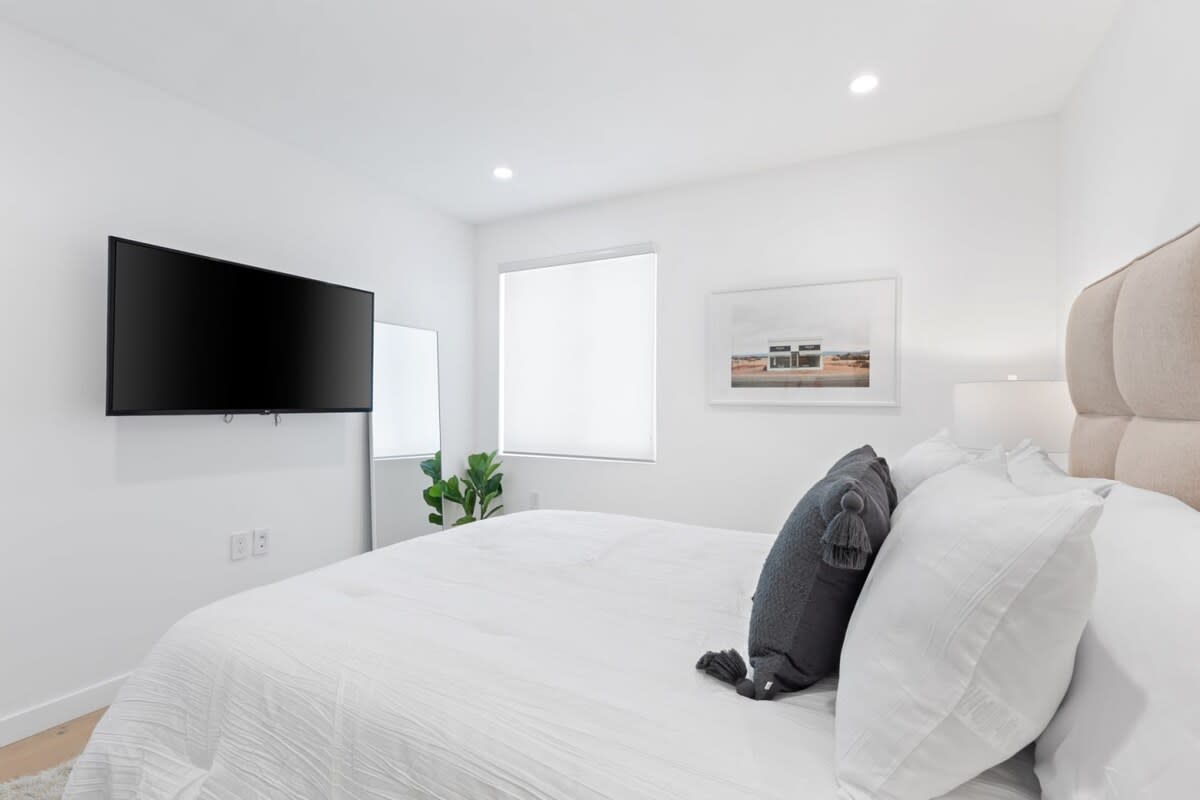 Relax in the upstairs master bedroom, featuring a smart tv and comfortable bed.