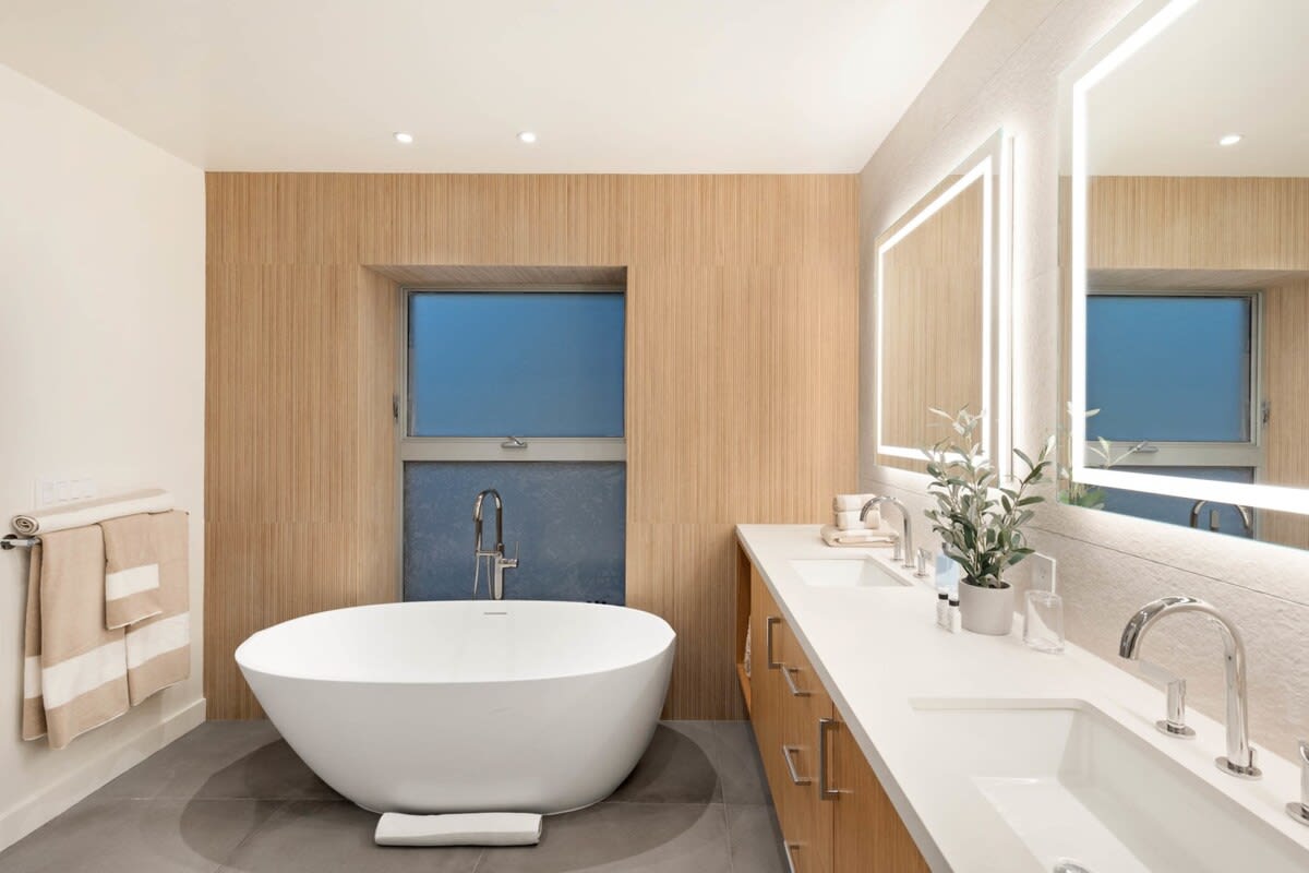 Primary bathroom with wooden touches, His & Hers sinks and a bathtub