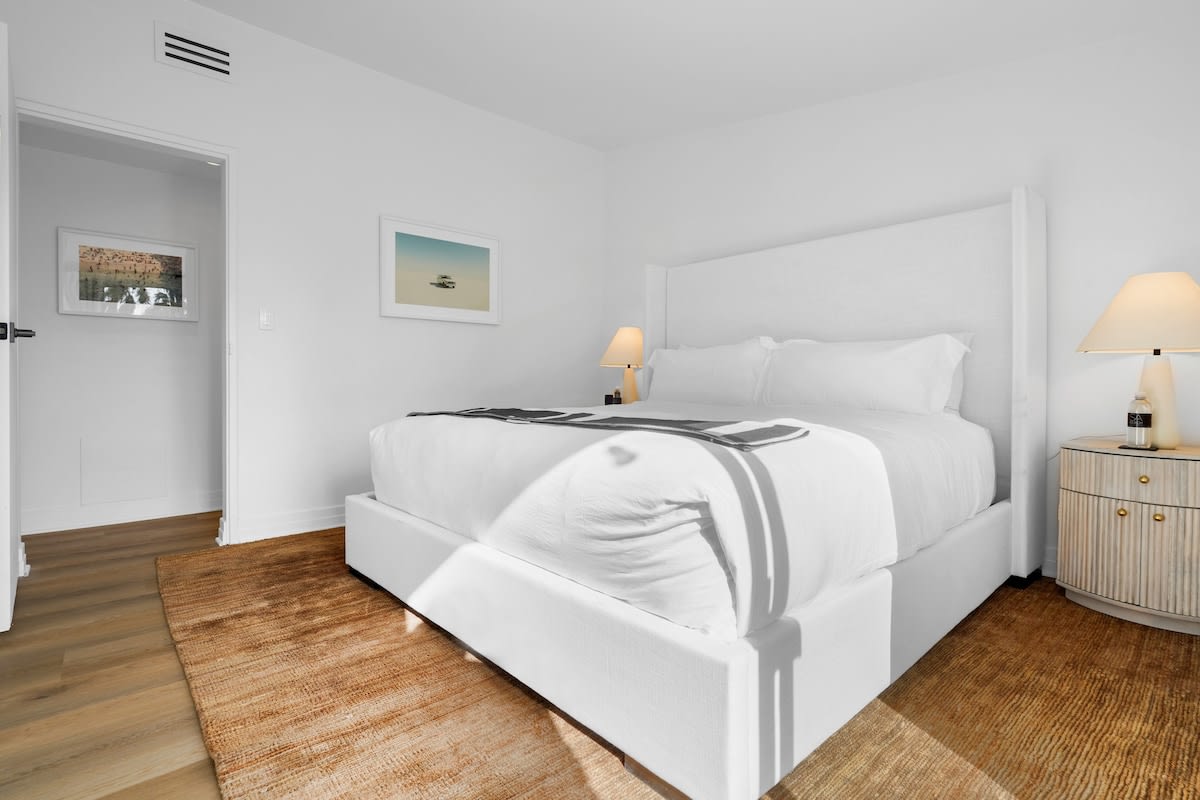 2nd guest bedroom with a linen king size bed, beach style side tables, stone side lamps, blackout shades, Smart TV, white hotel style linens and throw.