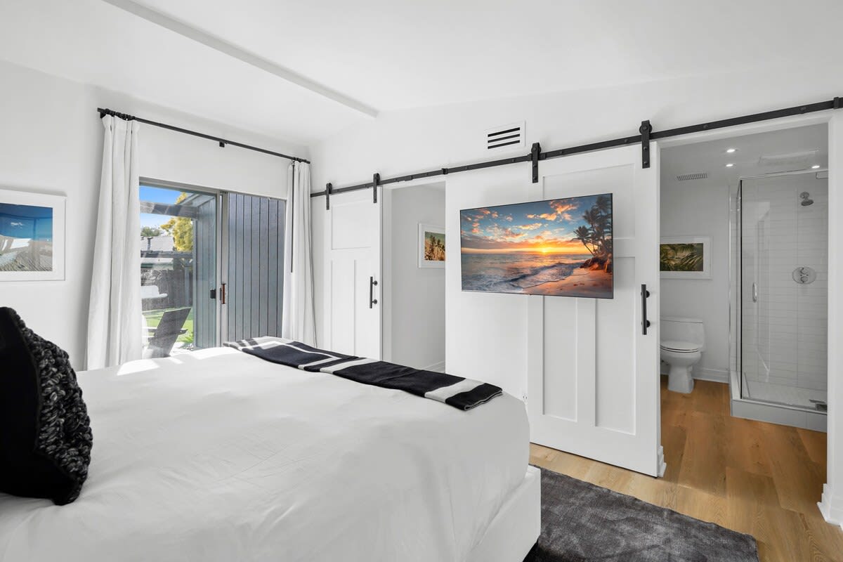 Luxurious master bedroom featuring large performance rug, marble side lamps, linen bed with hotel style linens and jute woven accent pillows, cashmere throw blanket, 55 inch flat screen smart TV. Ensuite bath with shower. Blackout shades.