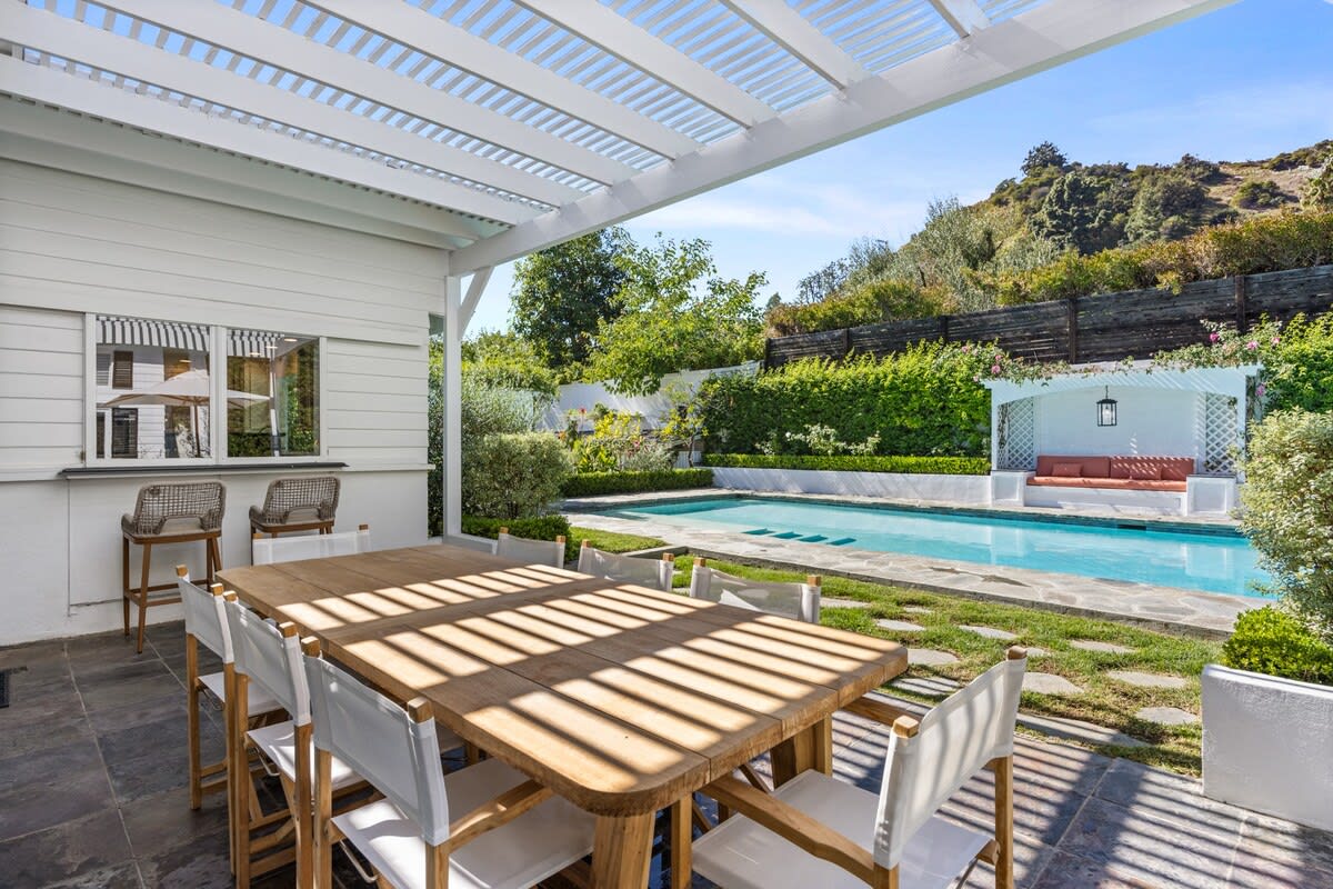Savor meals outdoors by the pool and grassy yard at the expansive alfresco dining table, providing a perfect setting for delightful moments in Beverly Hills.